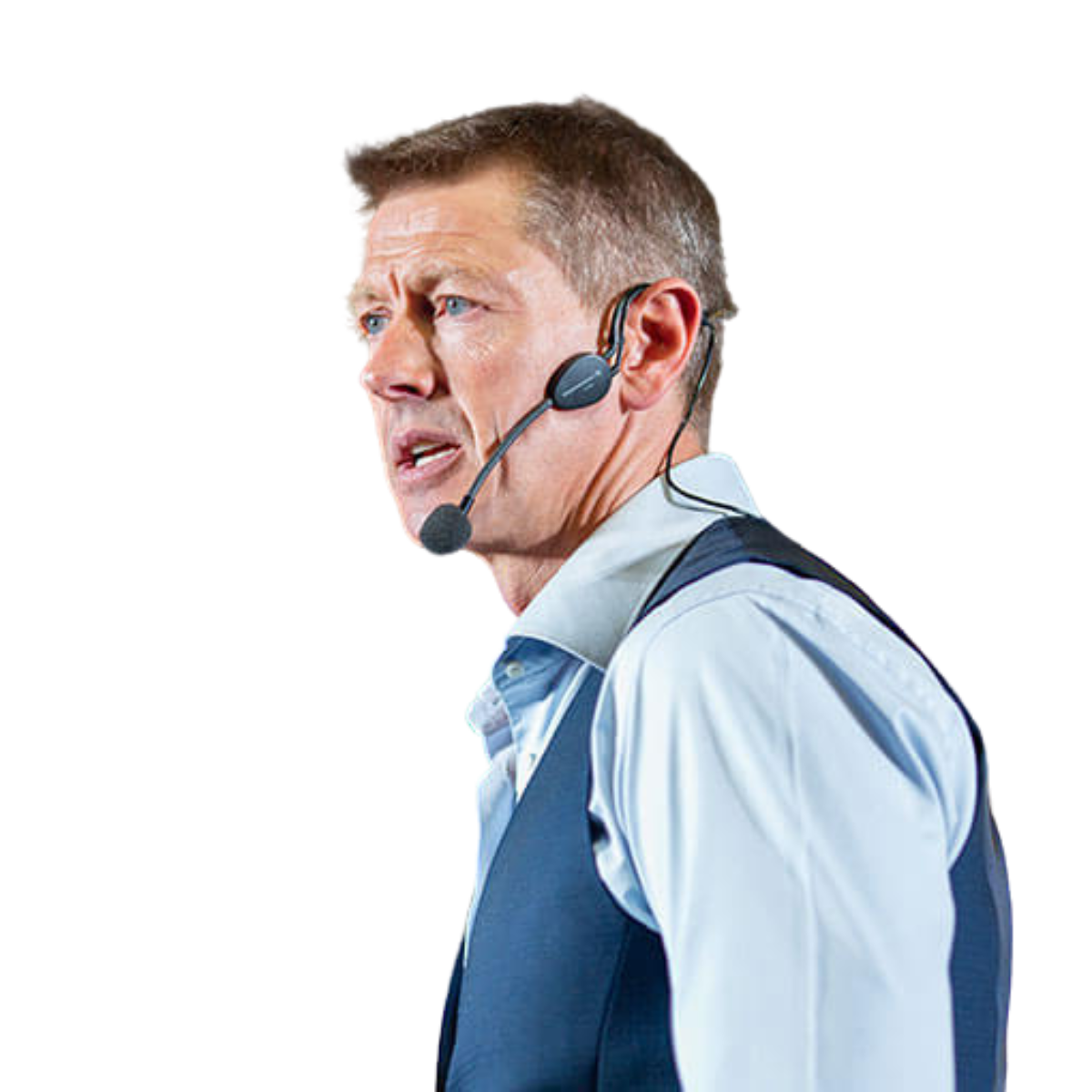 Man wearing a headset microphone, dressed in a light blue shirt and dark vest, speaking.
