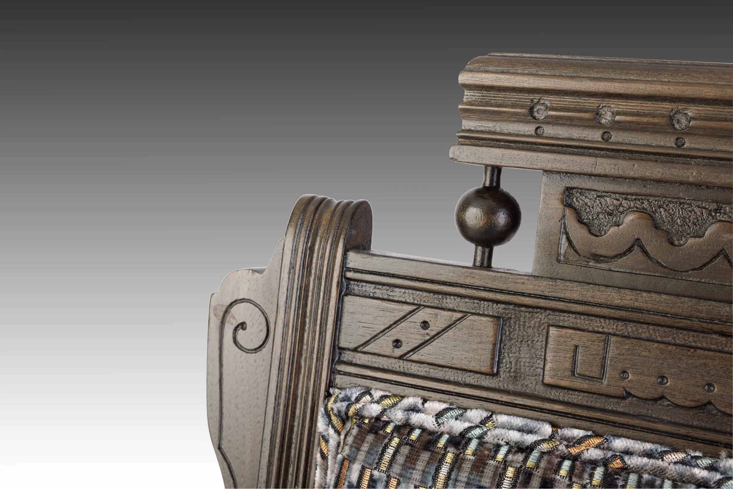 Close-up of carved crest rail and turned finials above printed jacquard velvet backrest.