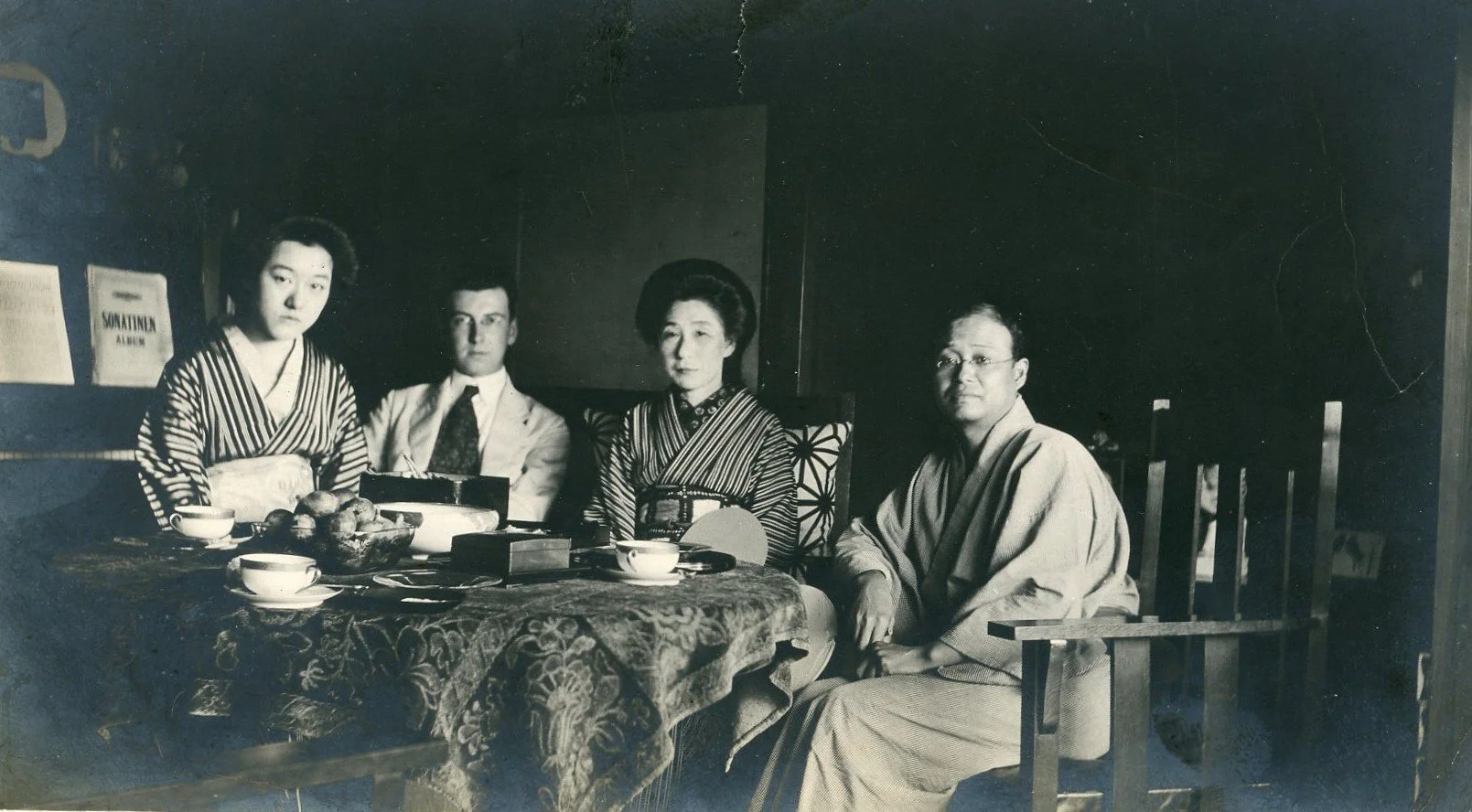Black-and-white photograph, Japan 1917: four people seated at a table, two of them in kimono.