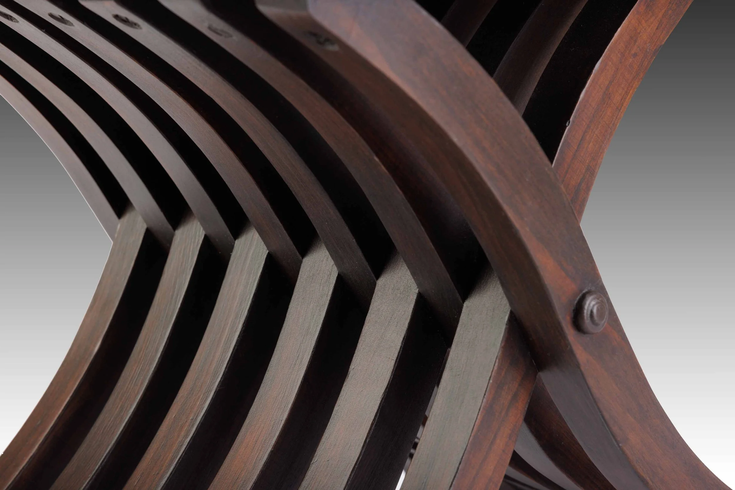 Close-up of curved slatted wooden frame on a Renaissance Revival chair, highlighting craftsmanship and sculptural form.