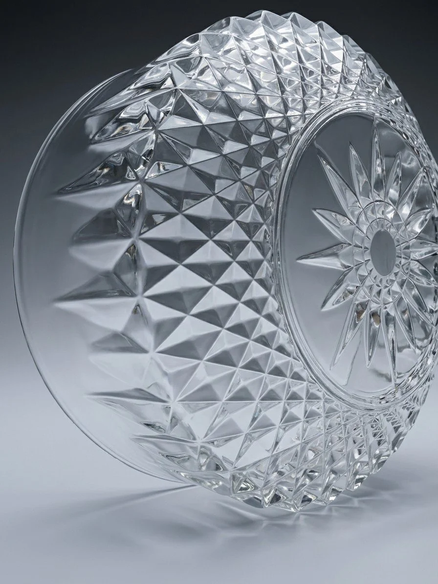 A pressed-glass bowl tipped onto its side against a grey ground, the outside wall covered in sharp diamond points and the base showing a molded star radiating from a plain round center