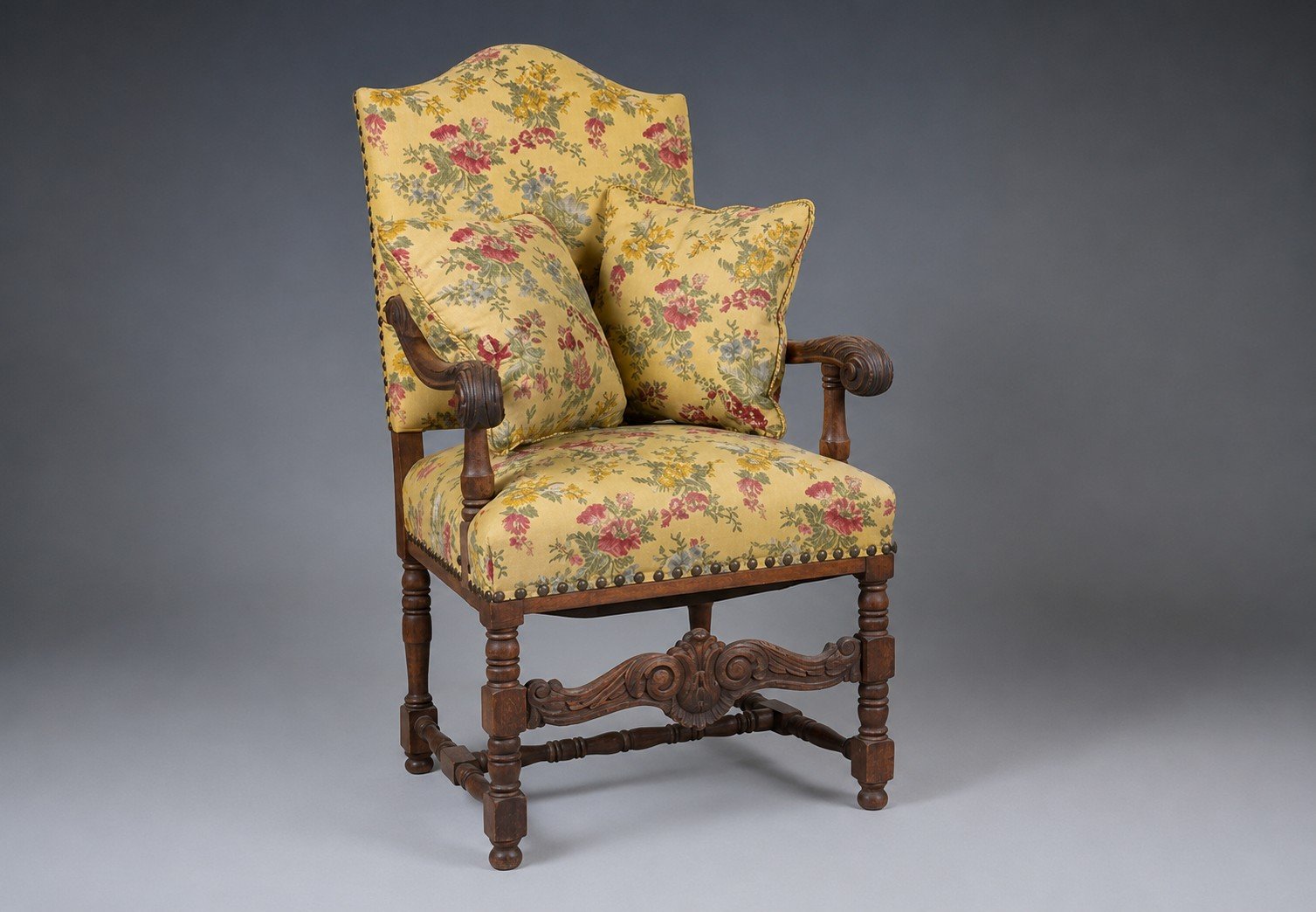 The Solstice Crest before restoration, in an earlier yellow floral covering with two matching cushions, its carved oak frame on baluster-turned legs joined by a shaped, carved stretcher