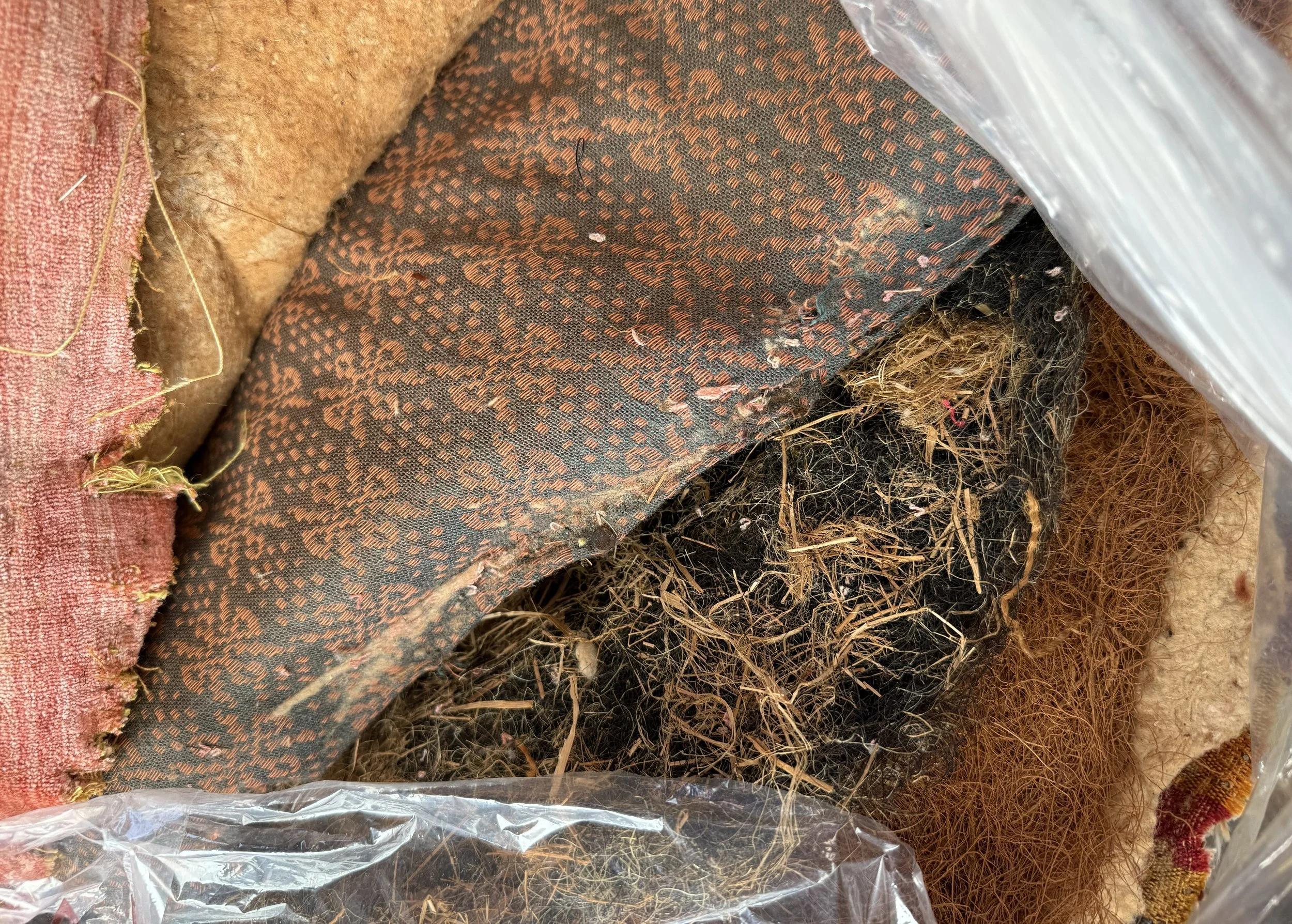 Interior upholstery materials removed from the slipper chair: horsehair, coir, cotton wadding, and two earlier cover fabrics.