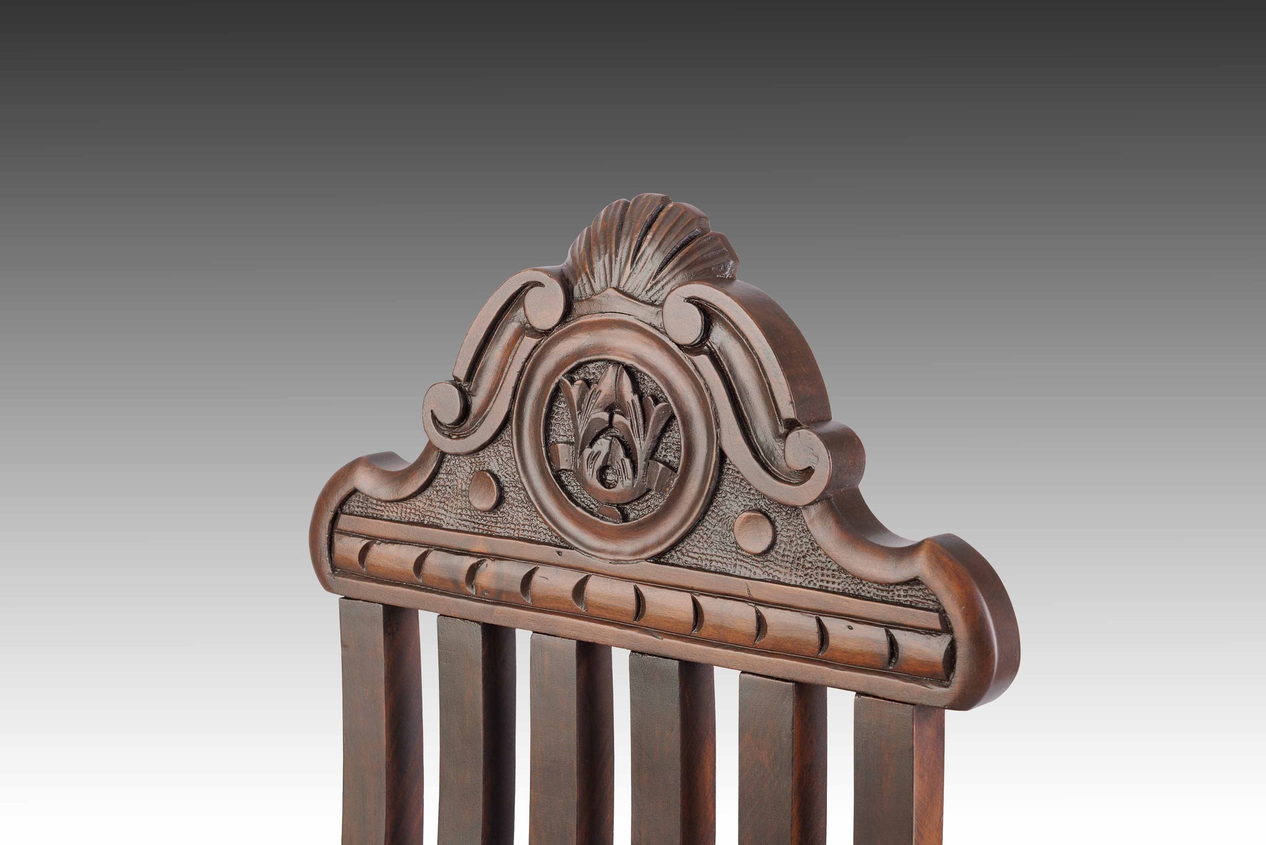 Carved wooden crest detail on a 19th-century Italian Renaissance Revival chair, showing scrollwork and central medallion.