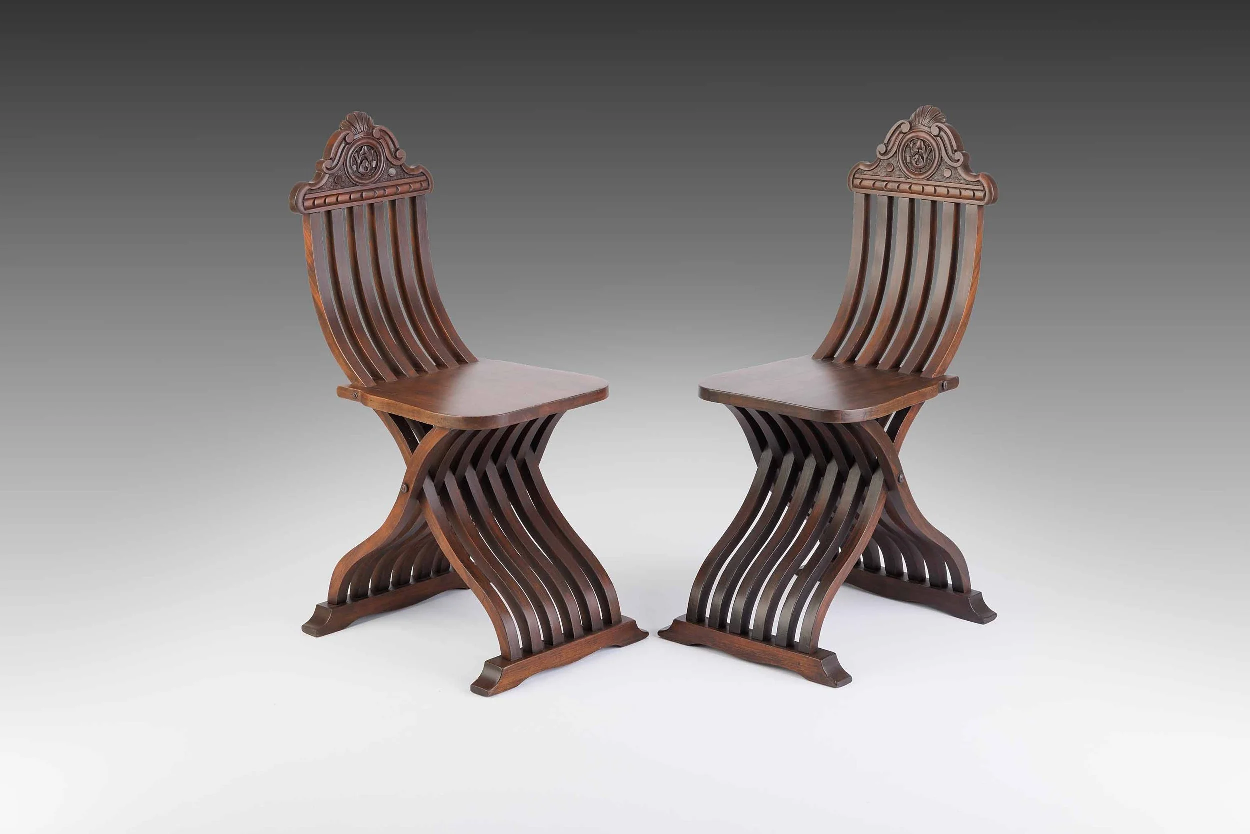Matched pair of 19th-century Italian Renaissance Revival chairs in sculptural sedia tenaglia form with curved slats and carved backrests, restored by Acanthus Home