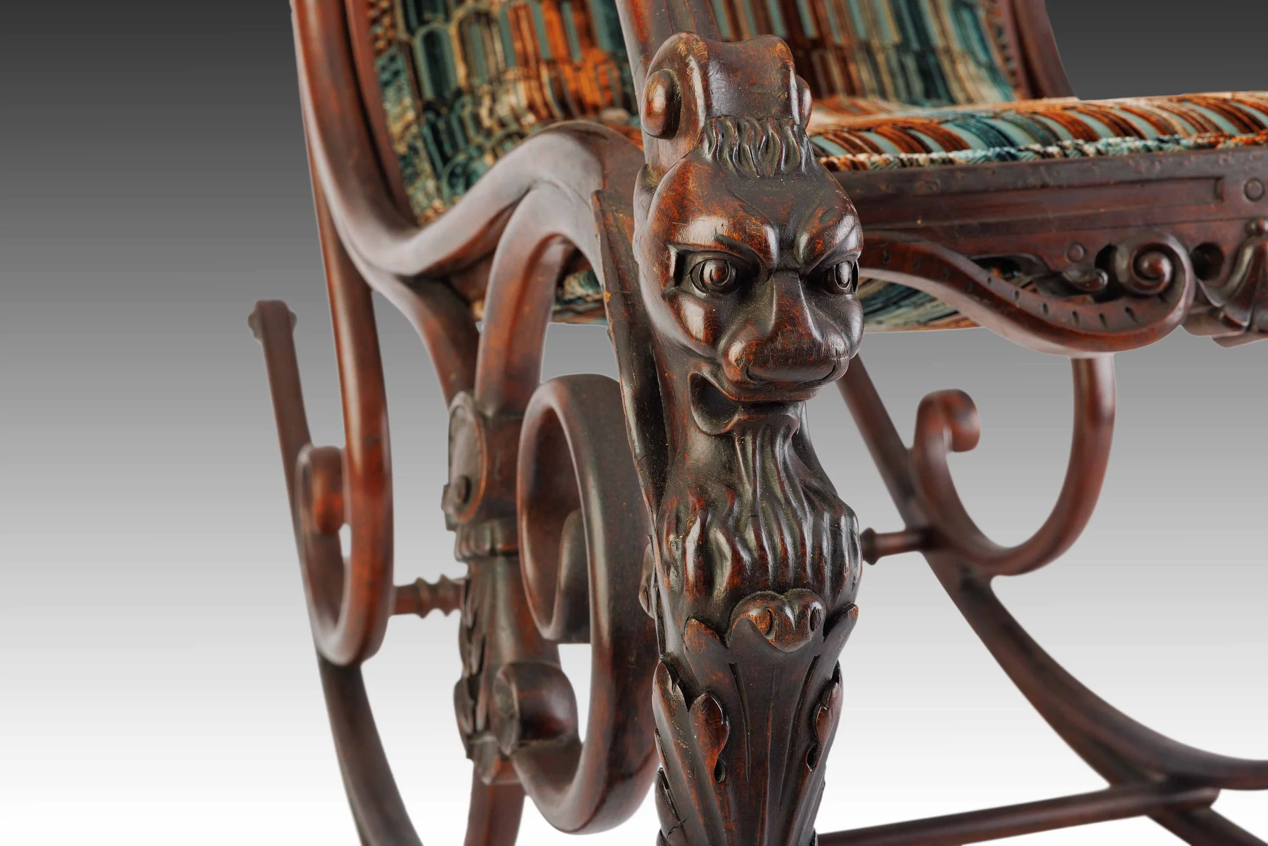 Close-up of The Lioncourt Rocker’s carved lion mask arm, showing expressive facial detail and aged patina of the wood.