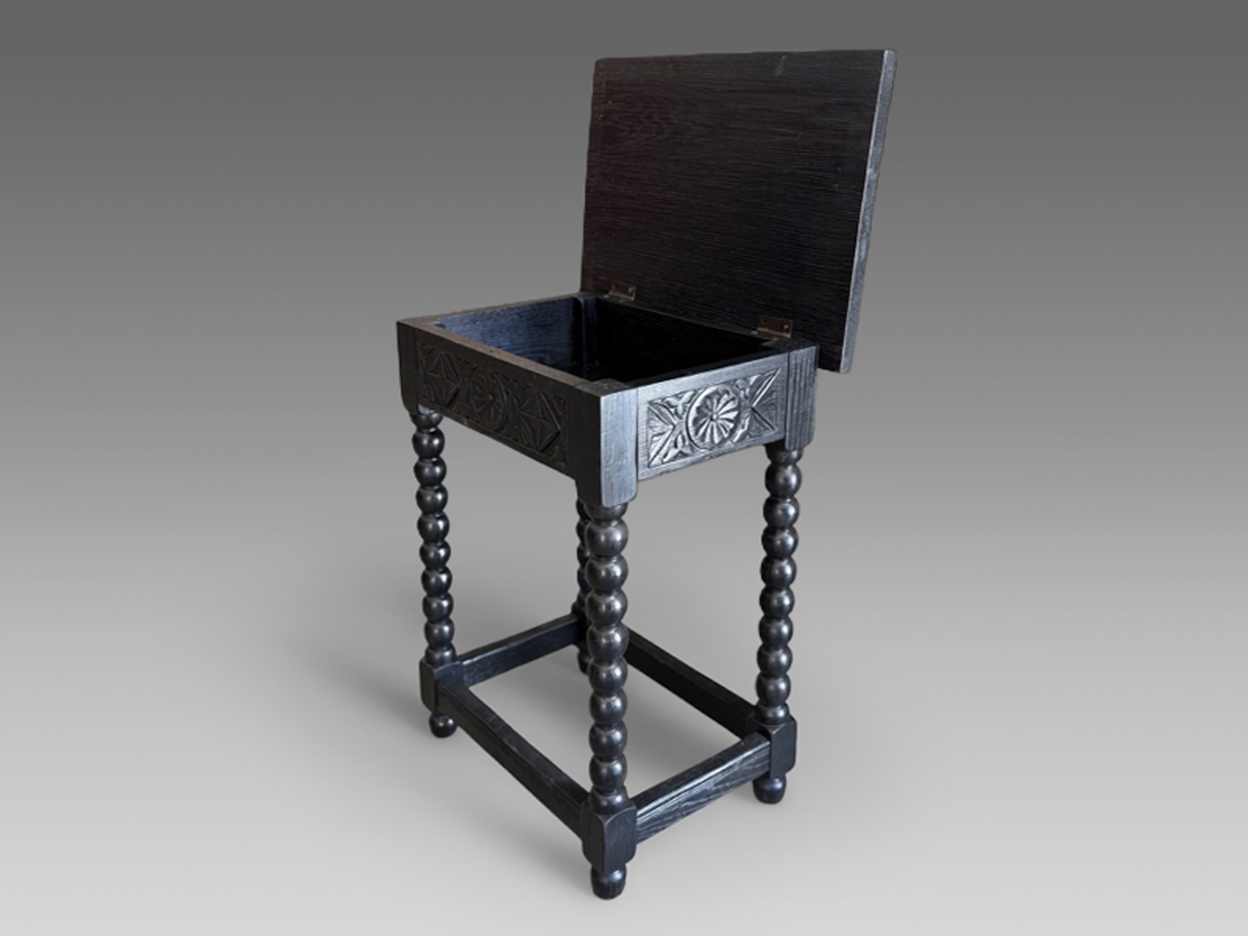 Spanish Revival flip top side table from the 1920s with carved geometric apron, turned legs, stretcher base, and black refinished wood surface with open top