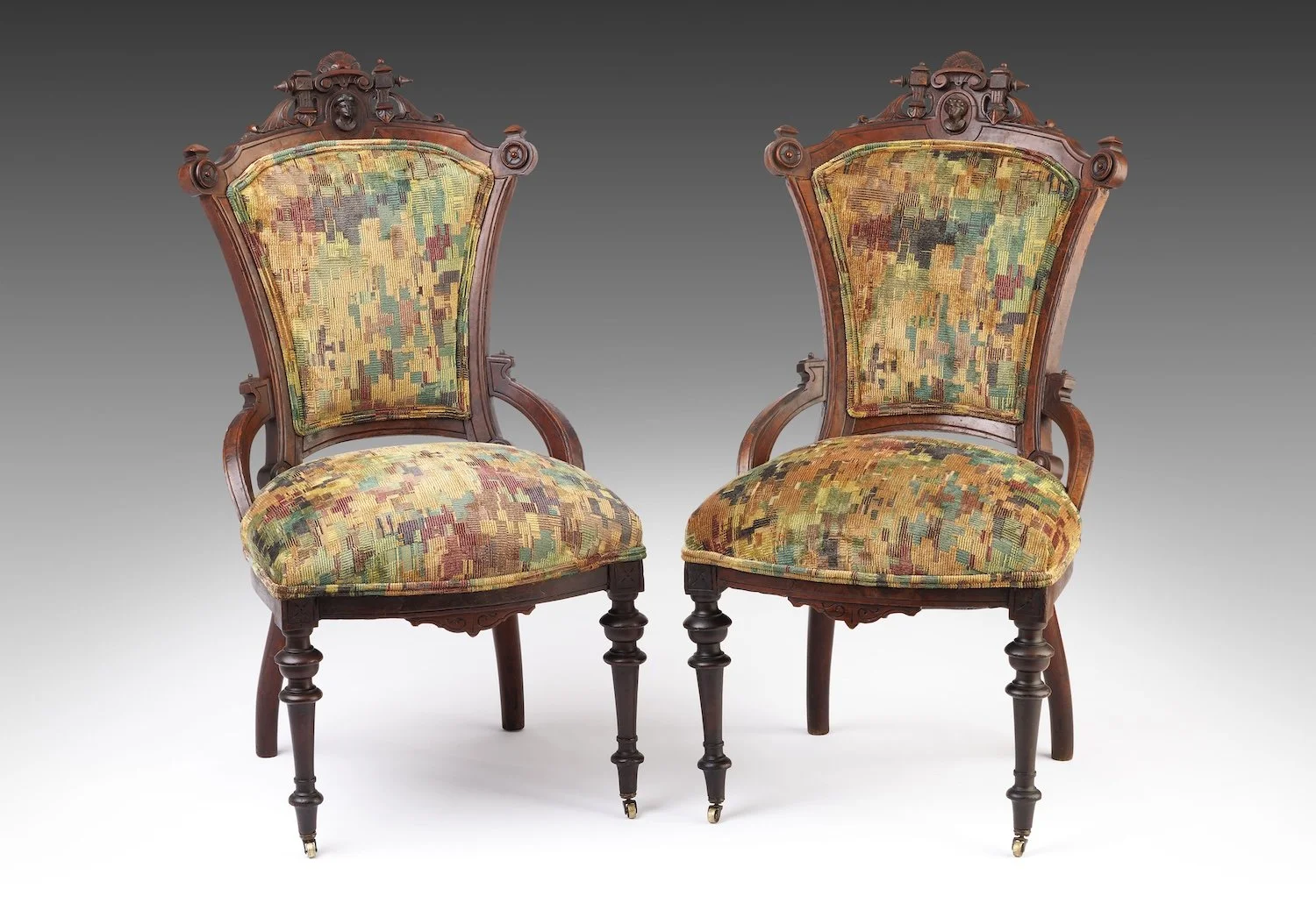 Pair of nineteenth-century walnut Renaissance Revival parlor chairs with carved portrait-medallion crests, reupholstered in Pierre Frey Gregorio Sotto Bosco velvet in golds, greens, reds, and blues.