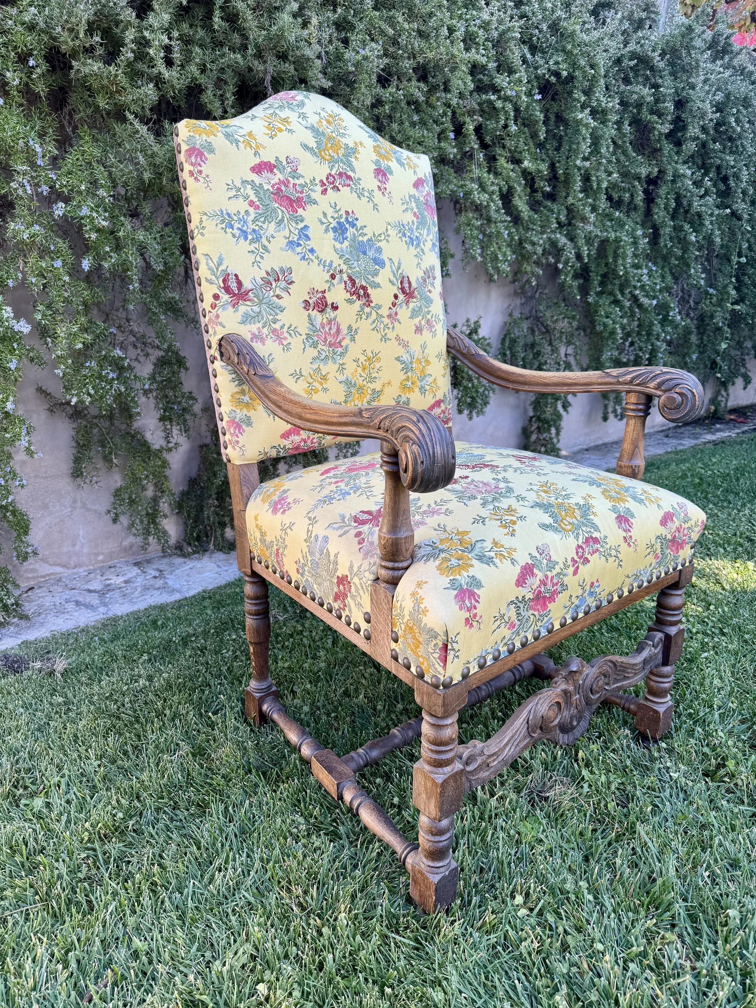 Antique carved oak armchair prior to restoration, showing original floral upholstery and softened surface condition.