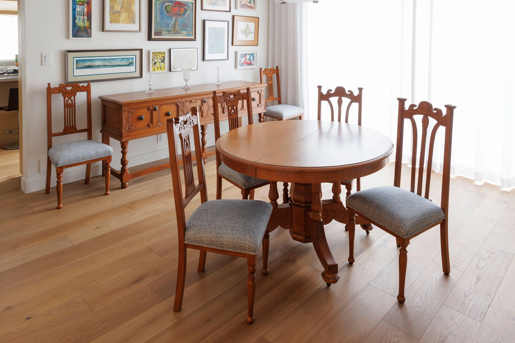 Antique Edwardian dining chairs and a round quarter-sawn oak table in a dining room, the Windward Collection, four lyre-backs and two splat-backs.