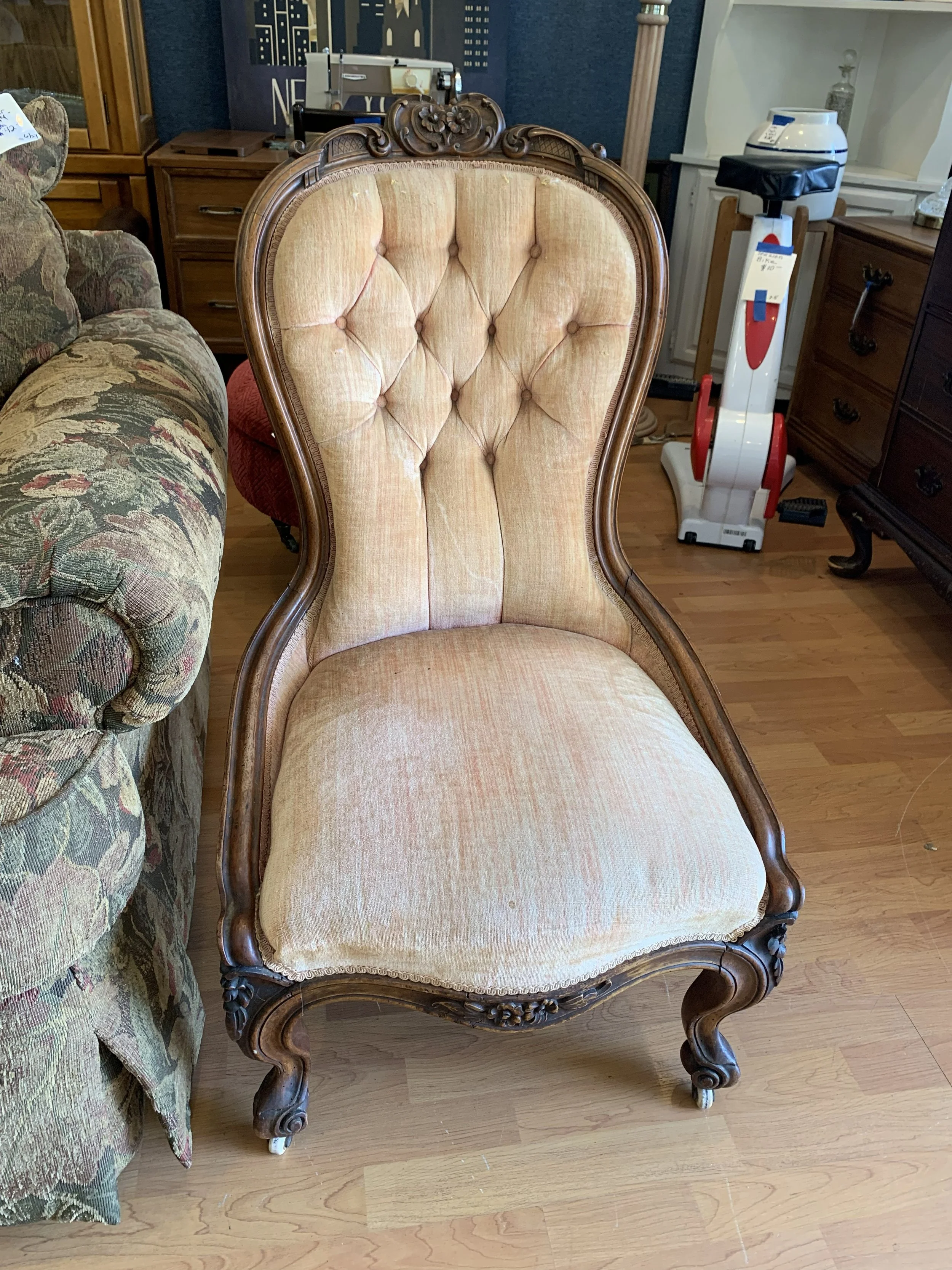 19th century Victorian slipper chair before restoration with tufted pink velvet upholstery, low profile seat, carved wood frame and original casters