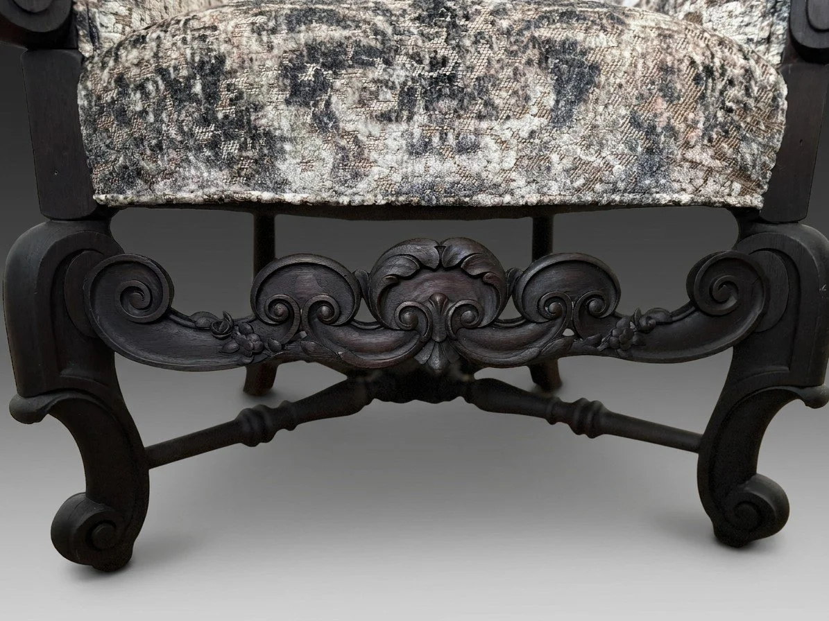 Carved scroll stretcher in low relief with turned cross-members, joining the splayed dark-stained legs of an antique tub chair