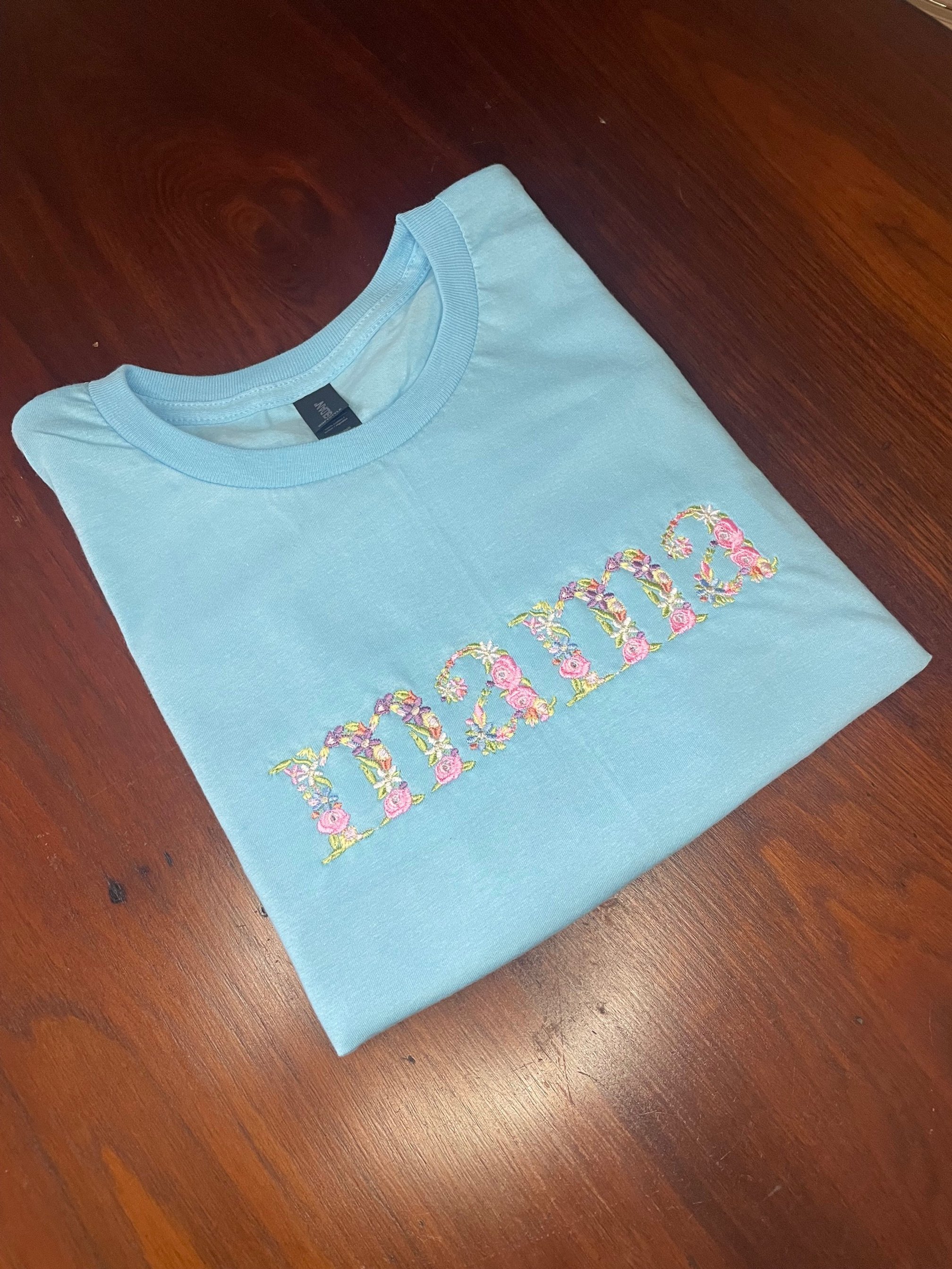 Light blue t-shirt with "mama" in floral embroidery.