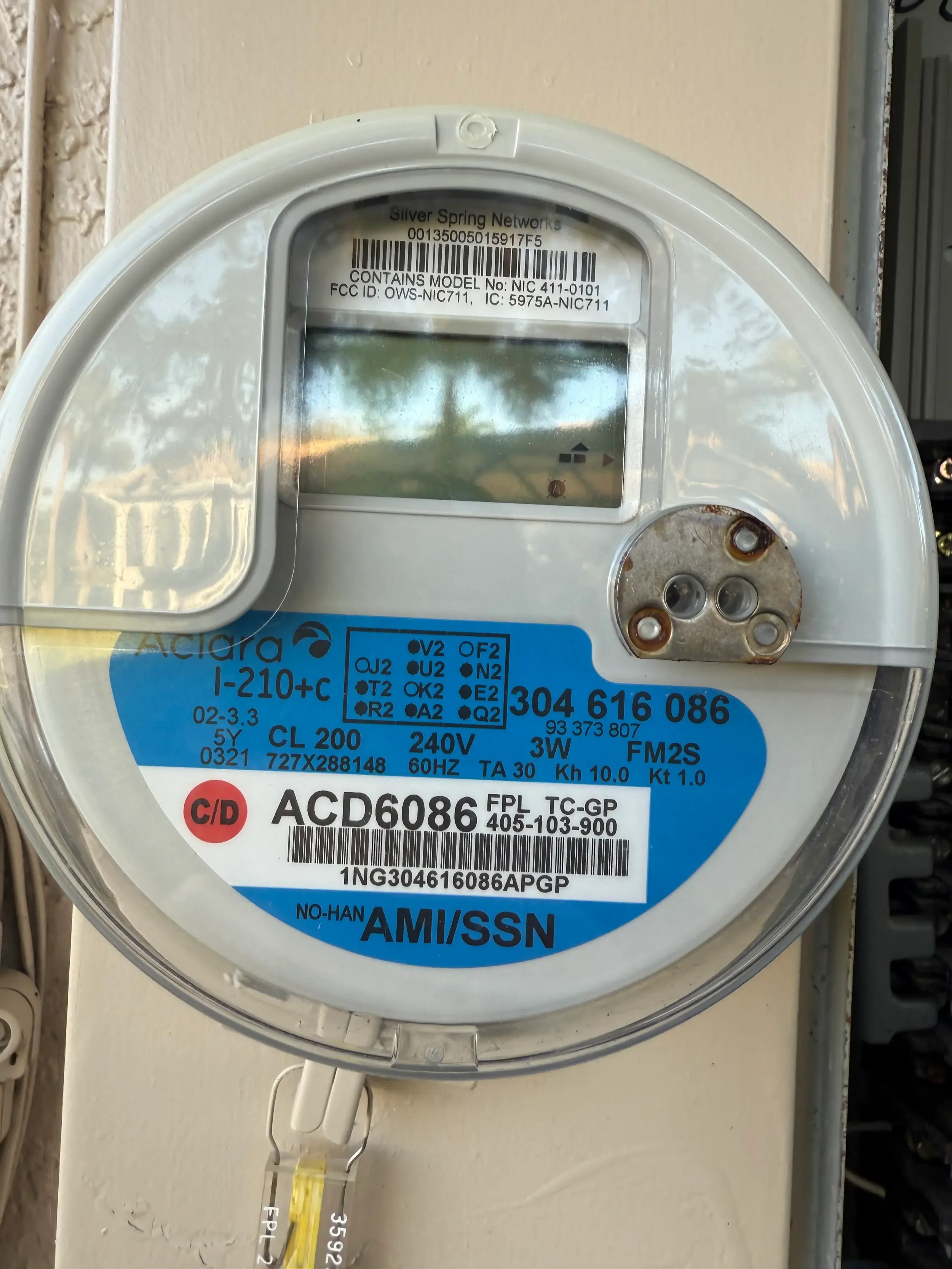 Close-up of a residential smart electric utility meter mounted on an exterior wall, displaying digital usage data and utility identification labels. This image highlights modern AMI smart meter technology used for accurate energy monitoring, remote m
