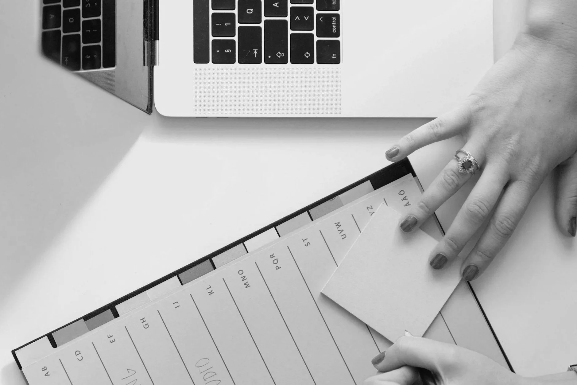 Person writing in a notebook next to a laptop