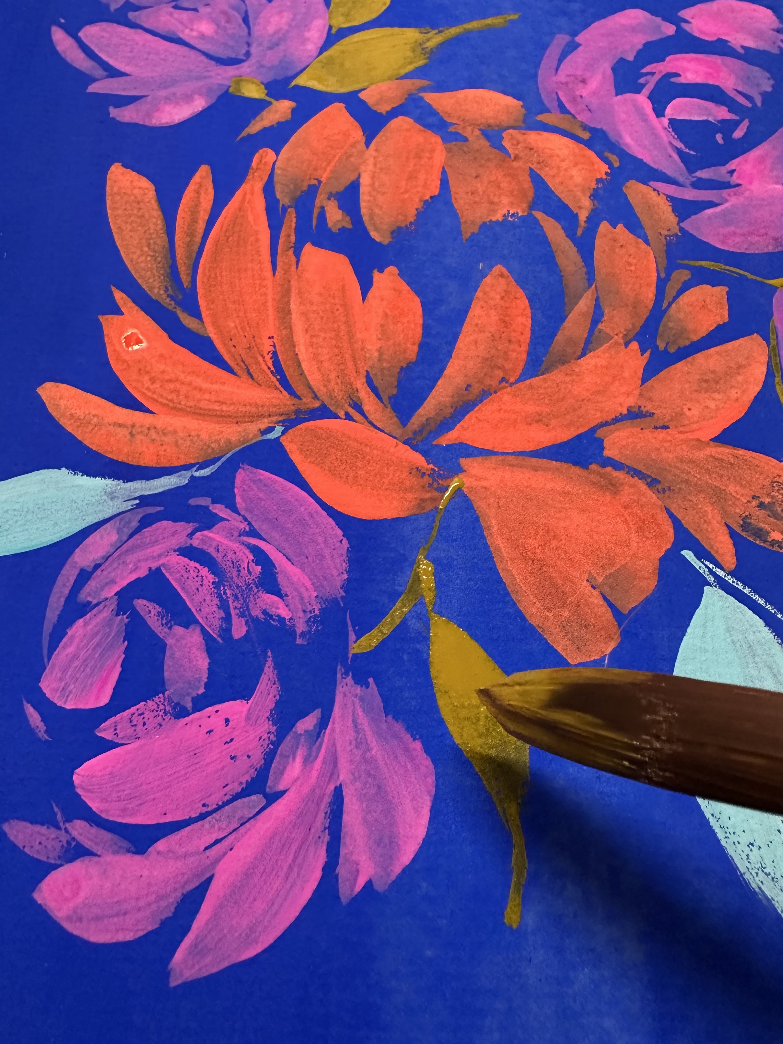 Vibrant floral painting on blue background, featuring red and magenta flowers with a brush adding mustard yellow details.