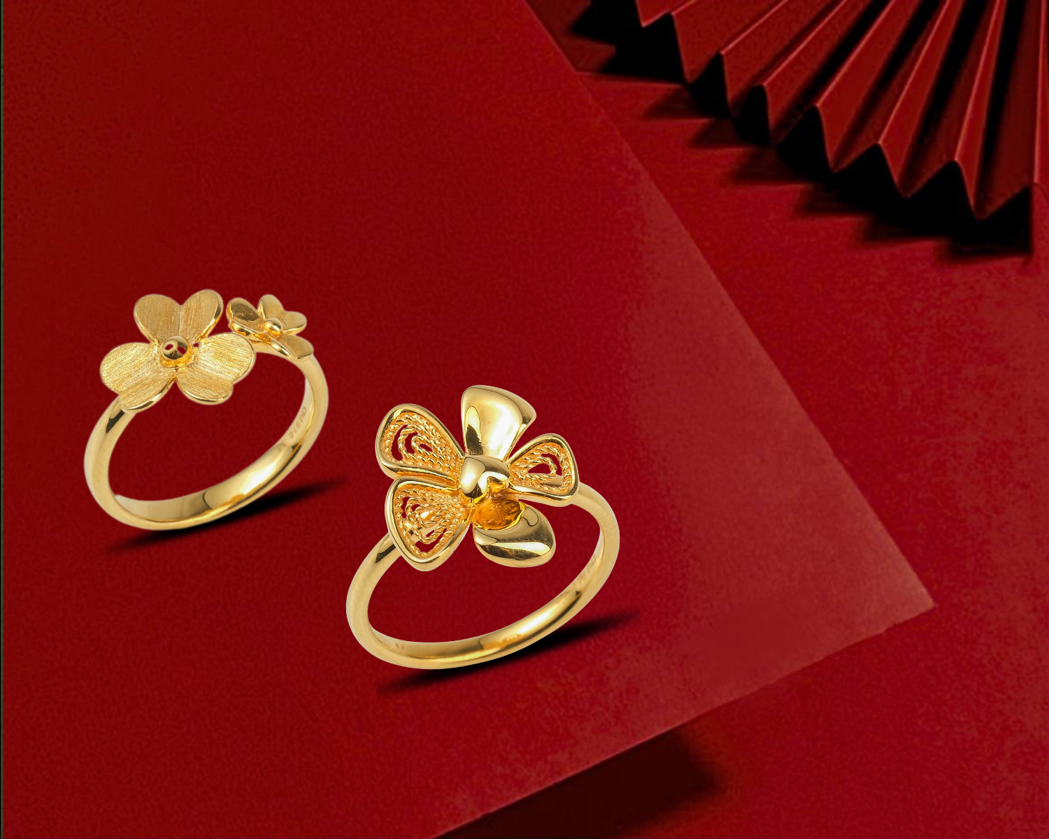 Two gold rings with flower designs on a red background.