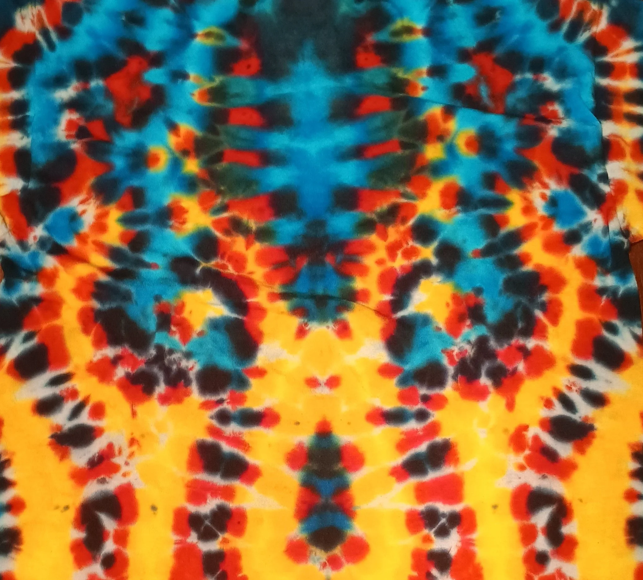 Close-up of a colorful tie-dye fabric with patterns in blue, red, orange, yellow, and black colors.