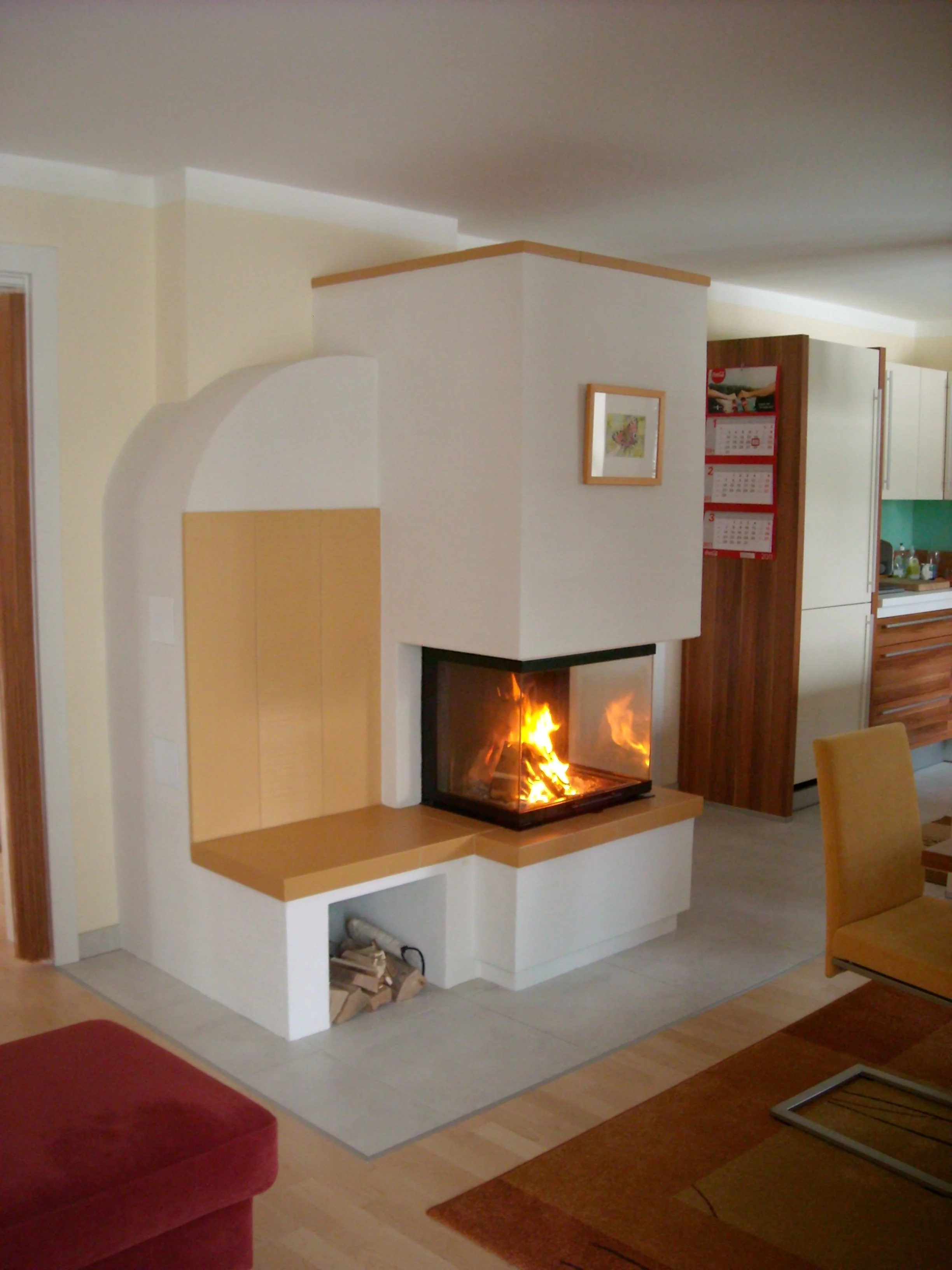 Einladender Wohnbereich mit einem Kaminofen, Holzscheiten und einem Feuer.