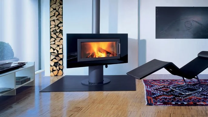 Moderne Wohnung mit Kamin, Holzablage und Relaxsessel auf einem bunten Teppich.