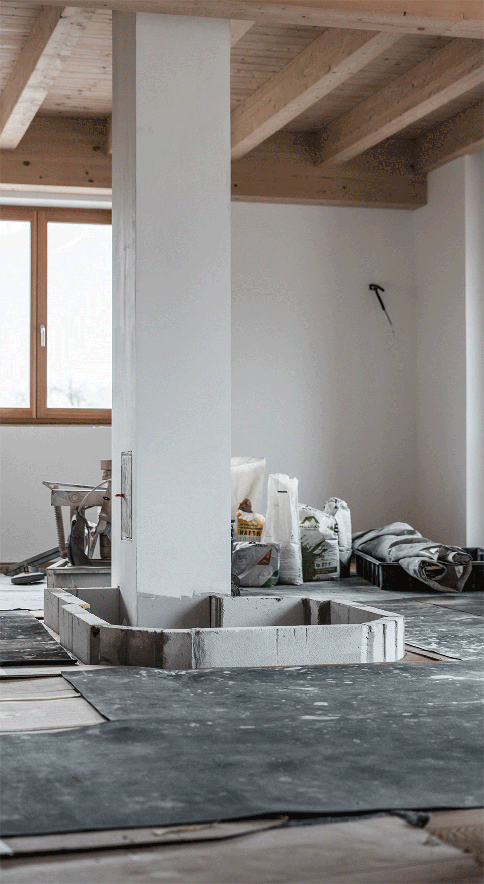 Innenraum eines Hauses, schrittweise wird der Aufbau eines modernen Kachelofens gezeigt.