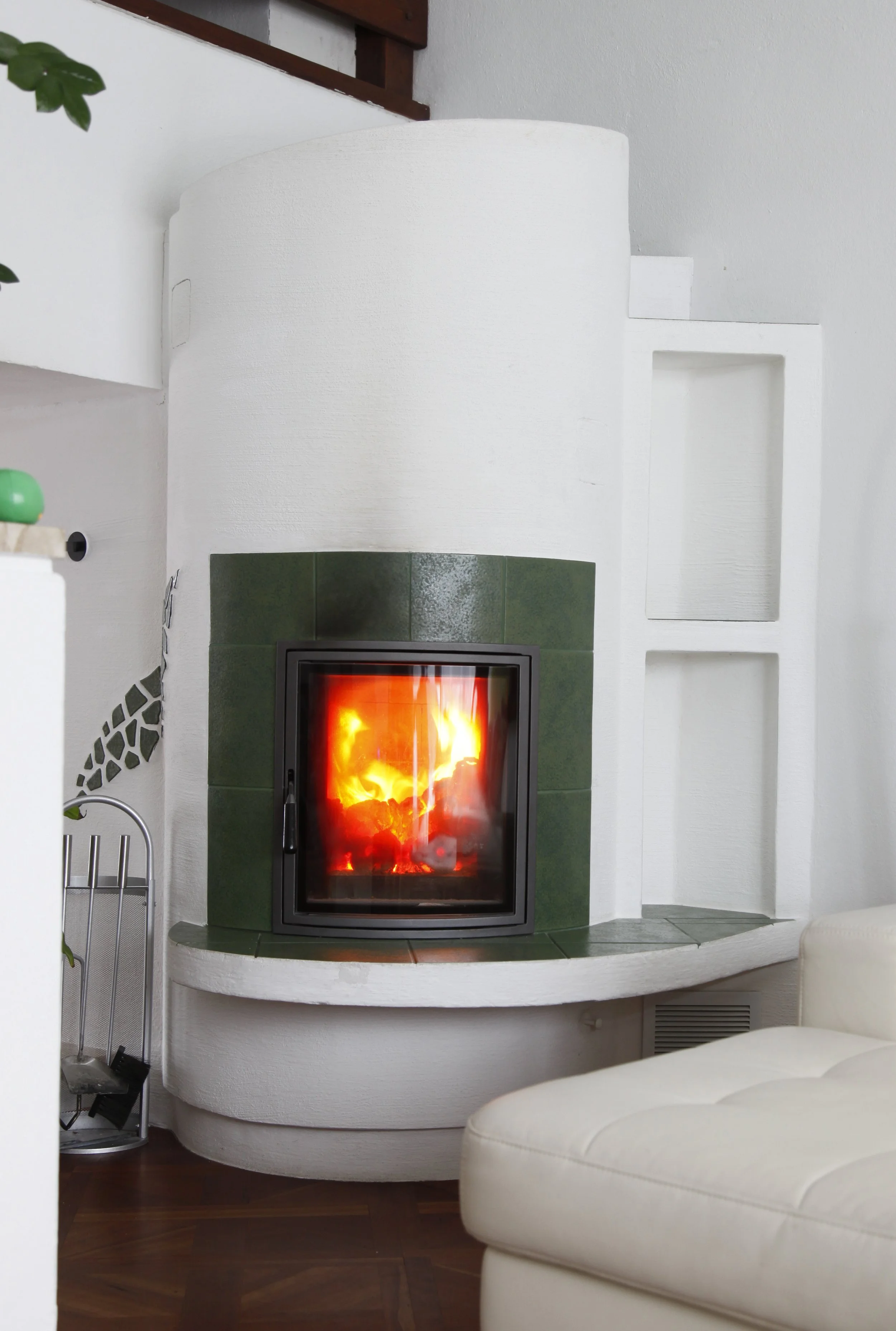 Kamin mit Flammen in einem Wohnzimmer, Couch im Vordergrund, Holzboden.