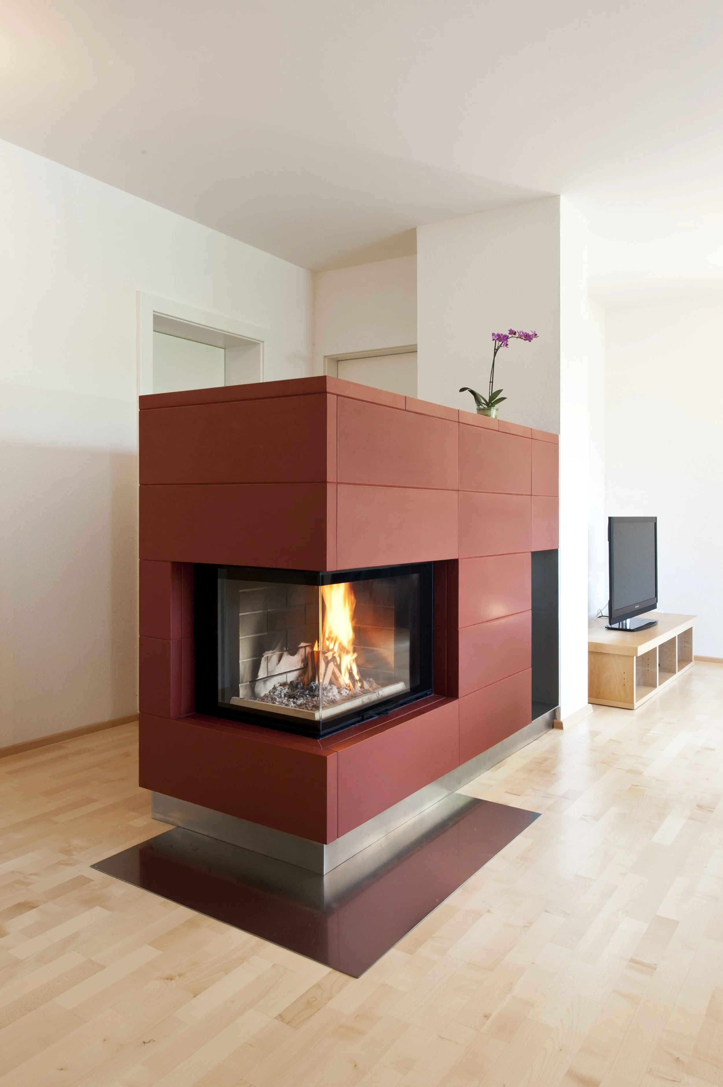 Moderner Kamin in einem hellen Wohnzimmer, mit Flammen sichtbar.