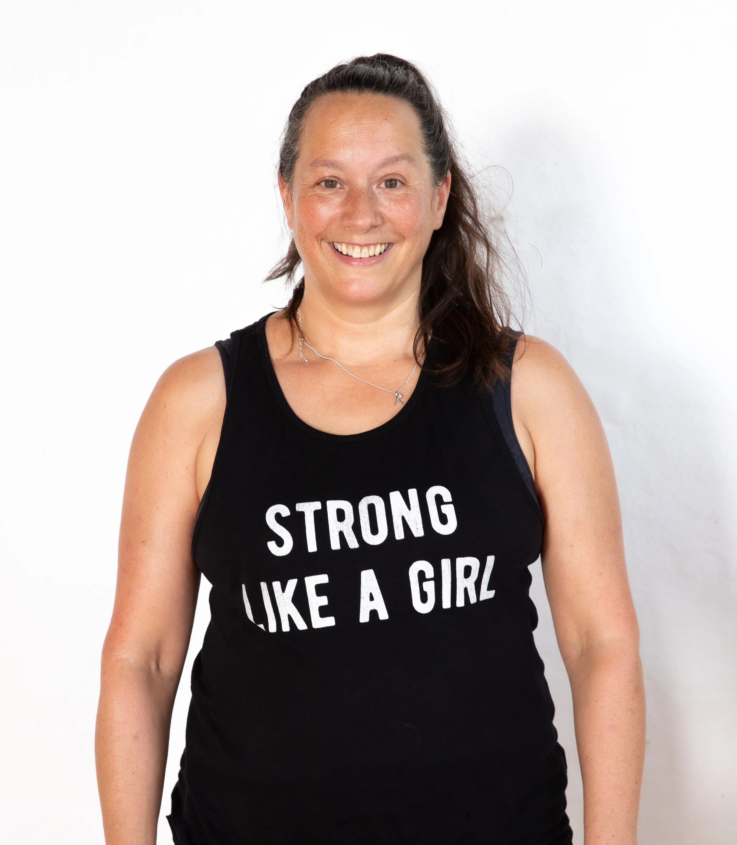 Abby Lord Senior Master trainer in Hypopressives standing facing the camera with a black vest top that says strong like a girl she is a pelvic floor and movement specialist