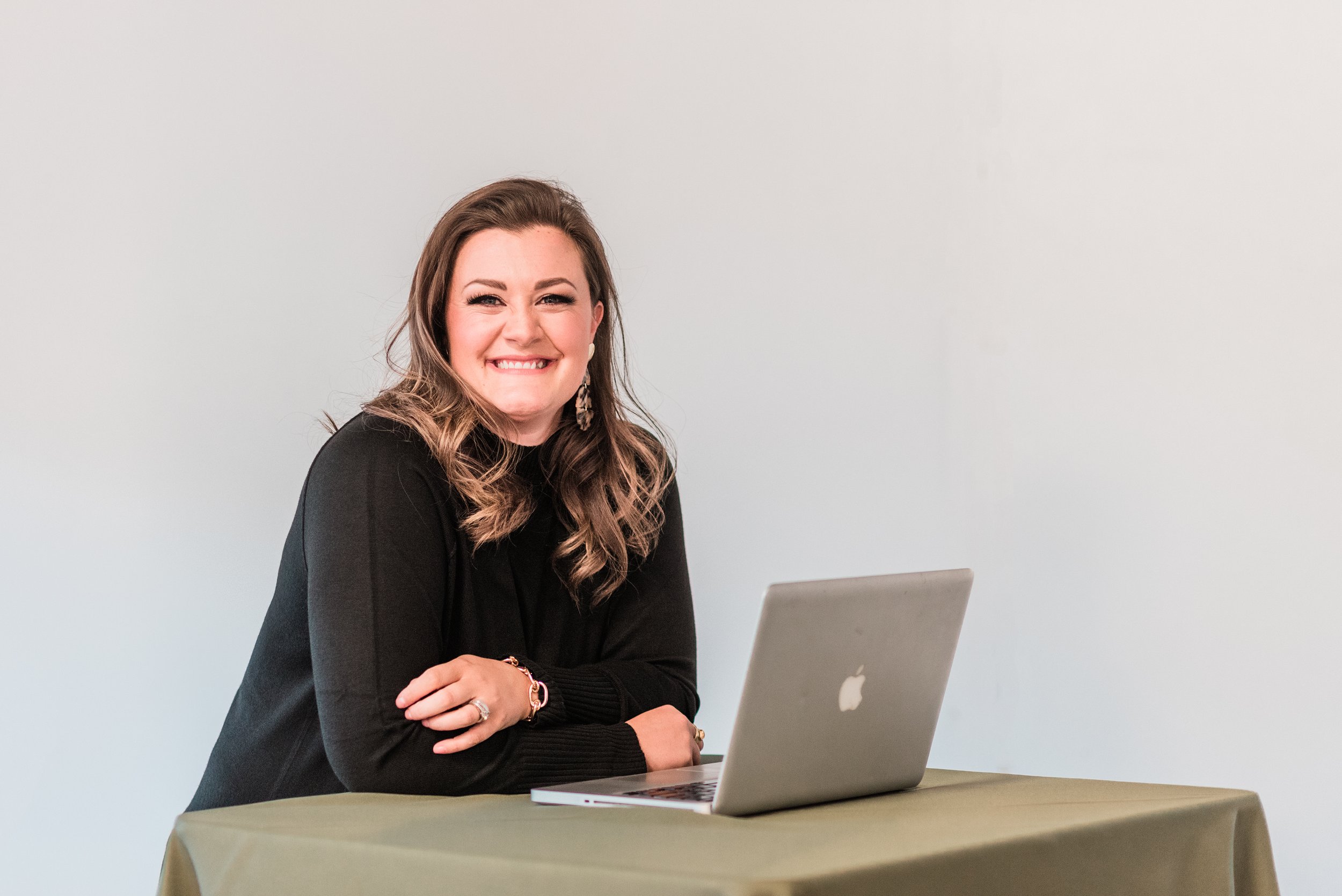 Kinsey Roberts, owner and founder of Vista View Events, modern mountain wedding venue in Rifle, Colorado, shown in professional headshot at laptop with welcoming smile. Leader in Colorado's wedding industry. Host of The Venue Podcast.