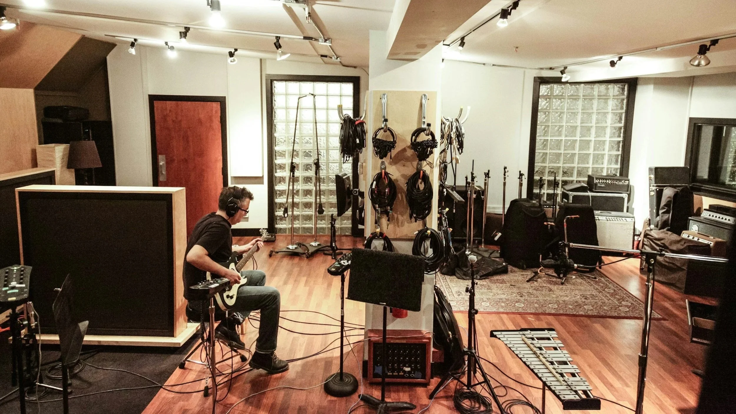 Musician recording guitar in a professional music production studio during a recording session.
