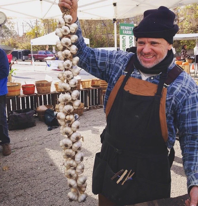 Henry with garlic braid at market.JPG