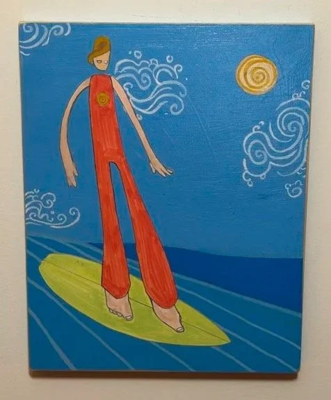 Painting of a woman wearing red overalls surfing on a yellow surfboard in a stylized ocean scene with a blue sky, clouds, and a sun.