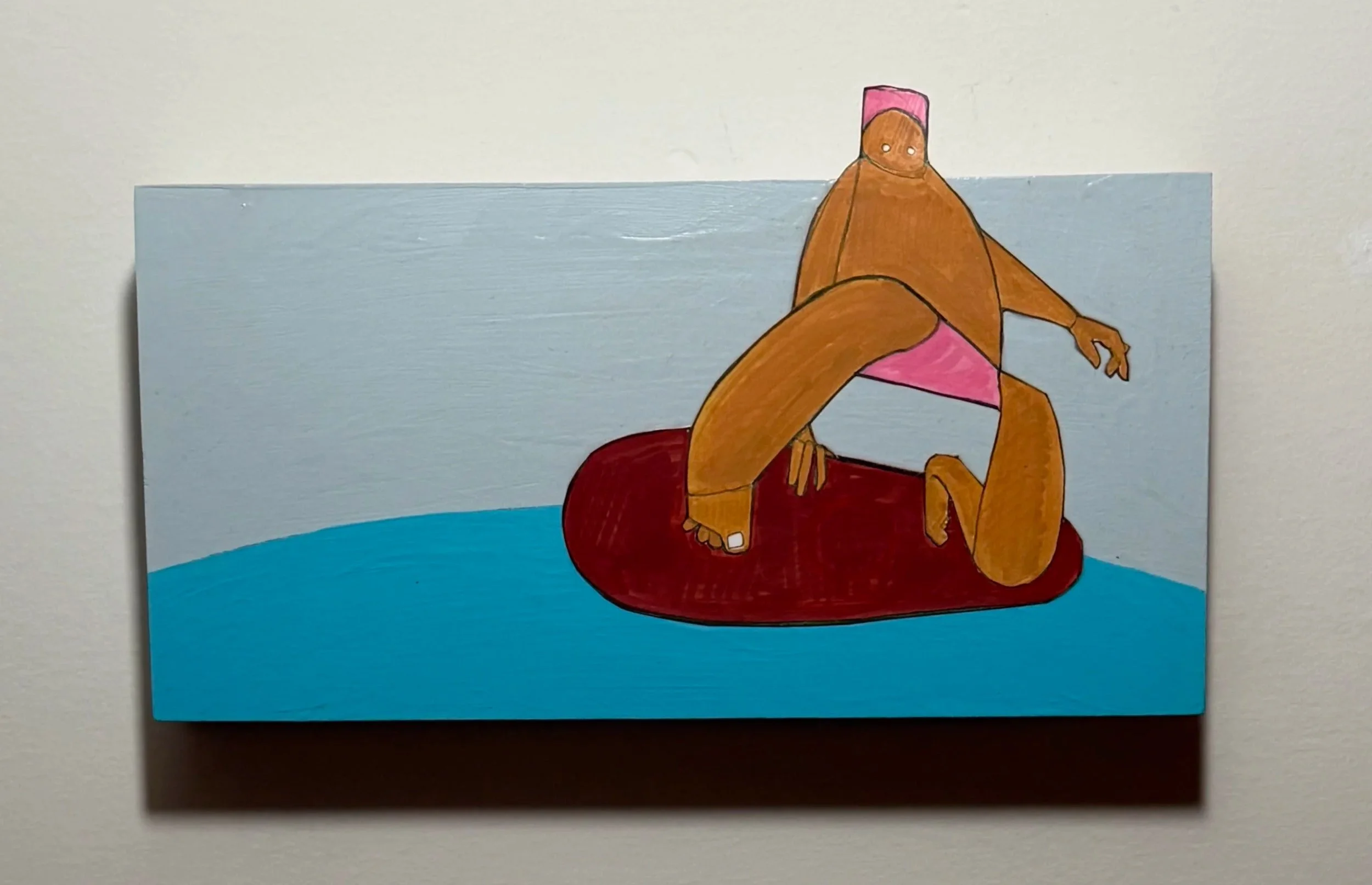 A colorful drawing of a person with brown skin sitting cross-legged on a red mat in front of a blue background. The person is wearing a pink head covering and orange clothing, with a simple face featuring two white eyes.