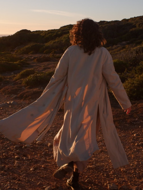 Person walking along a rocky path outdoors in warm evening sunlight.