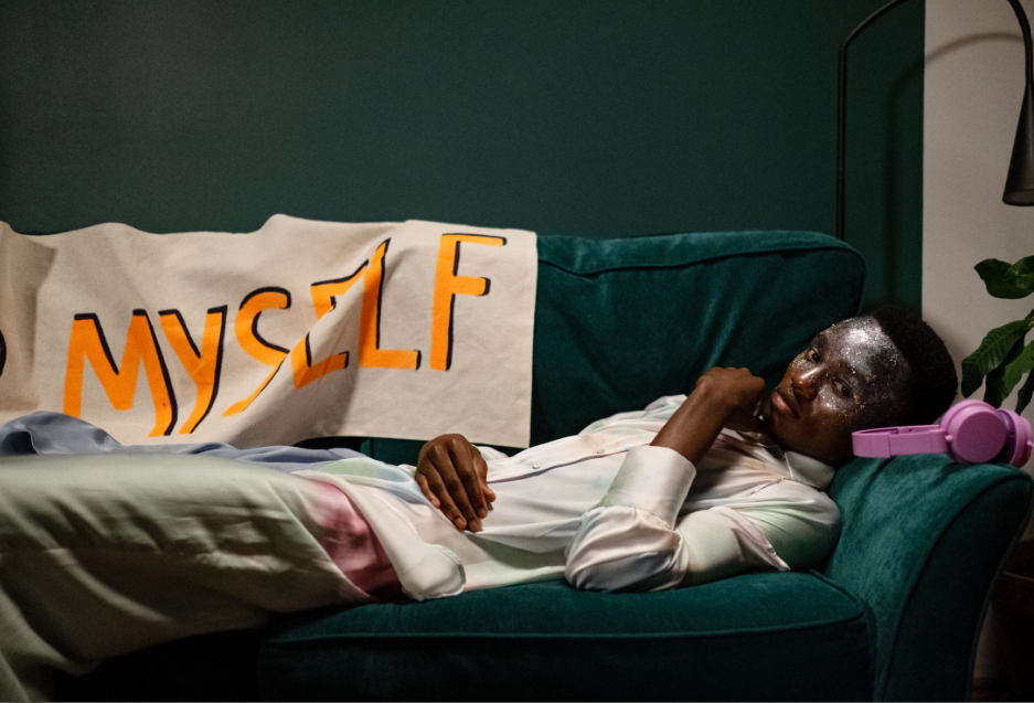 Person resting on a green couch beside artwork reading “MYSELF,” representing choosing yourself and breaking people-pleasing patterns.
