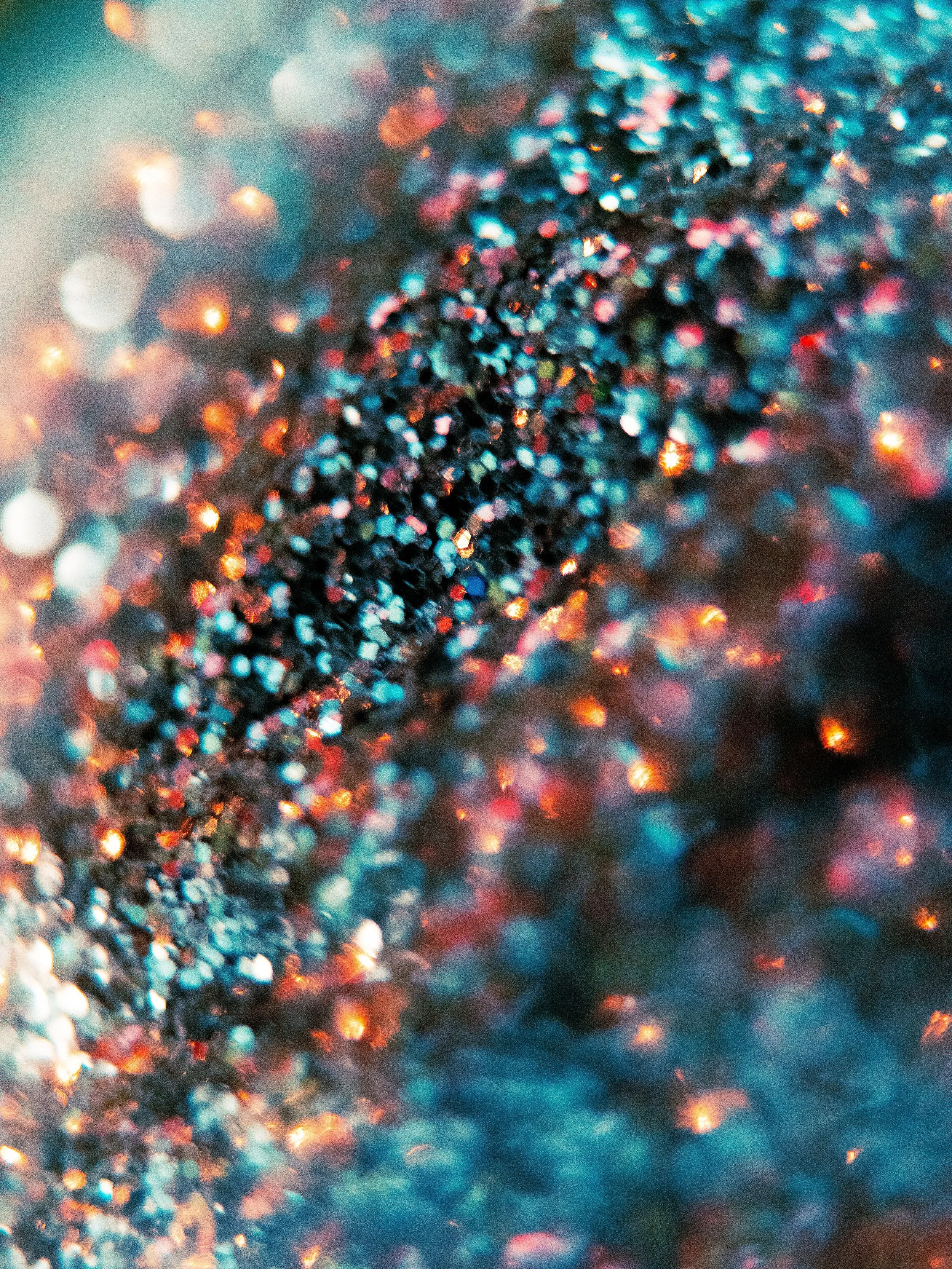 Abstract teal, coral, and pink light reflecting across a textured surface.