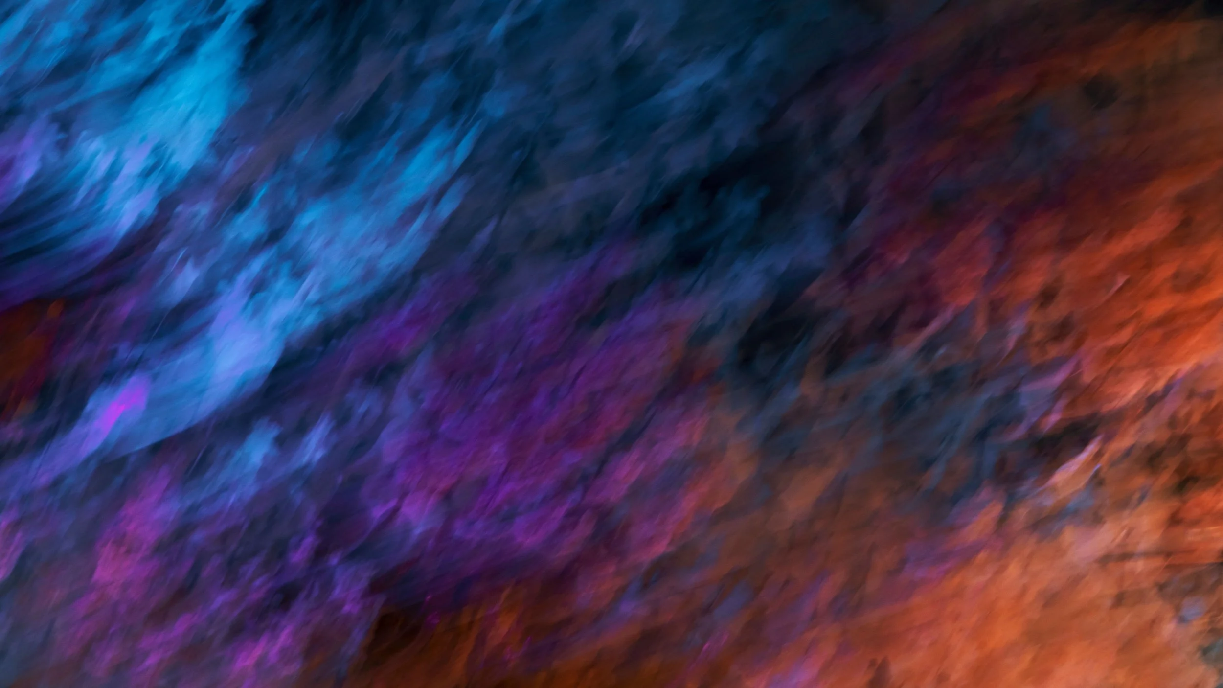Abstract blurred texture with flowing blue, purple, and warm orange tones.