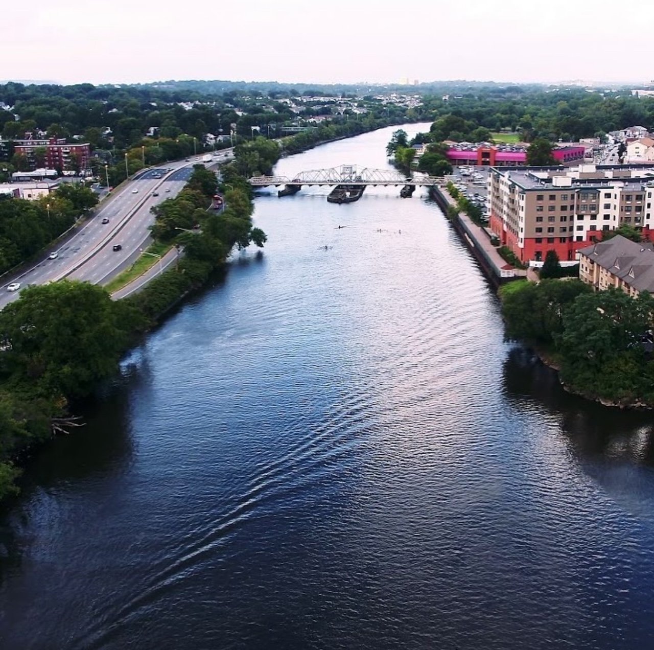 Aerial view of a river flowing through a city with buildings on both sides and a bridge crossing over the water.