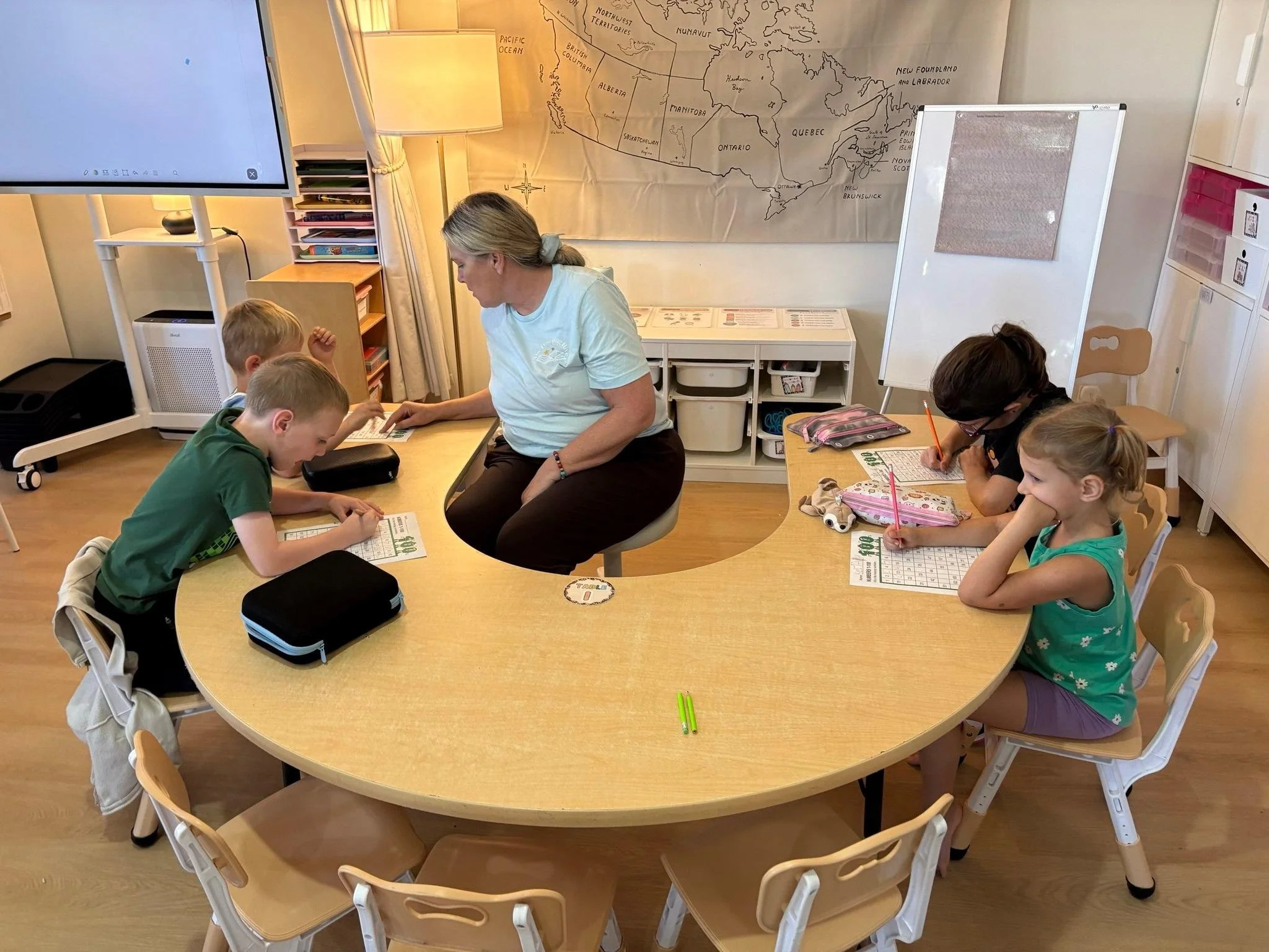 a kind female educator helping a student with their worksheet at private school in woodstock