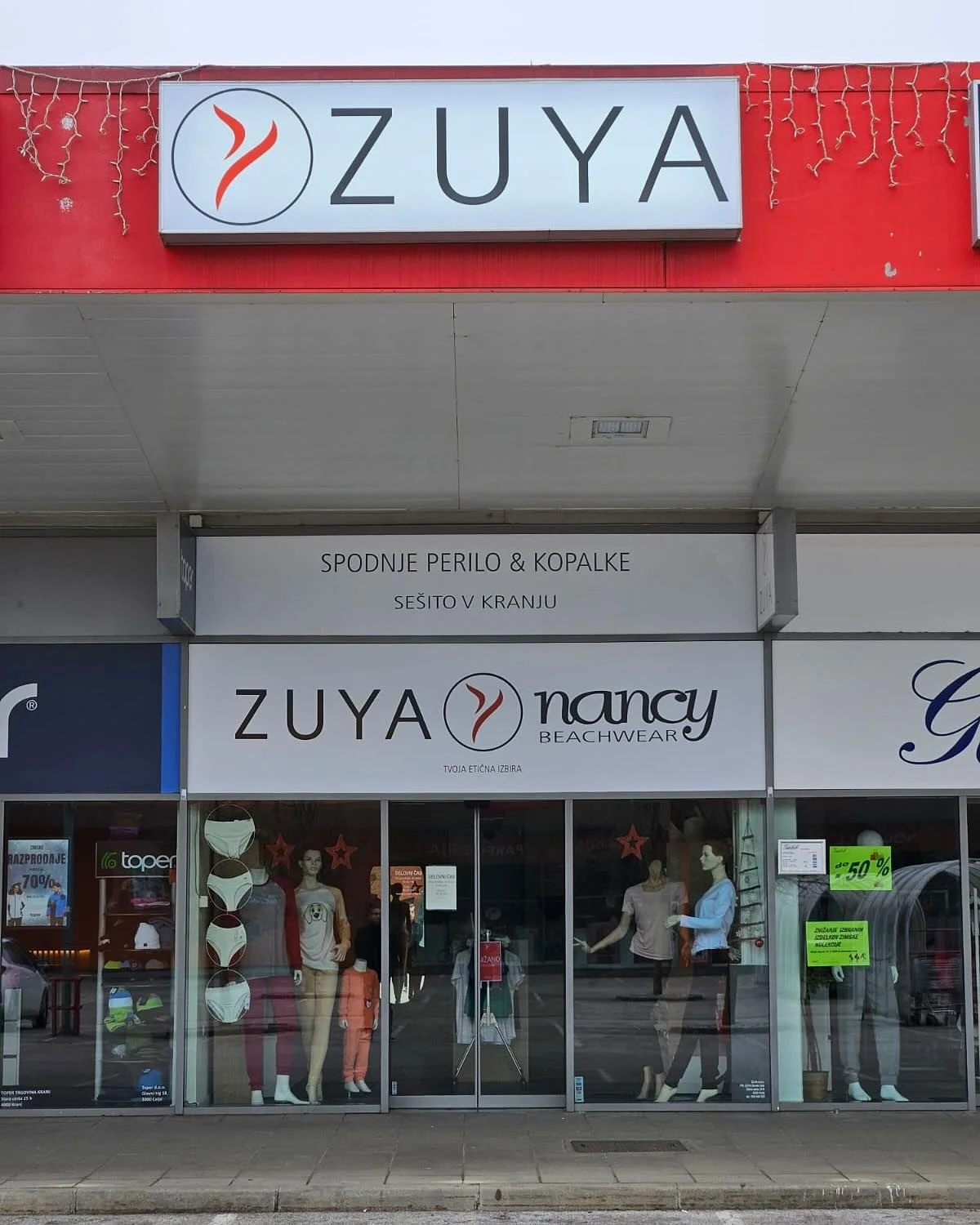 Izrezana folija z logotipom trgovine ZUYA – bela na steklu, ter svetlobni tabli, "light boxu"