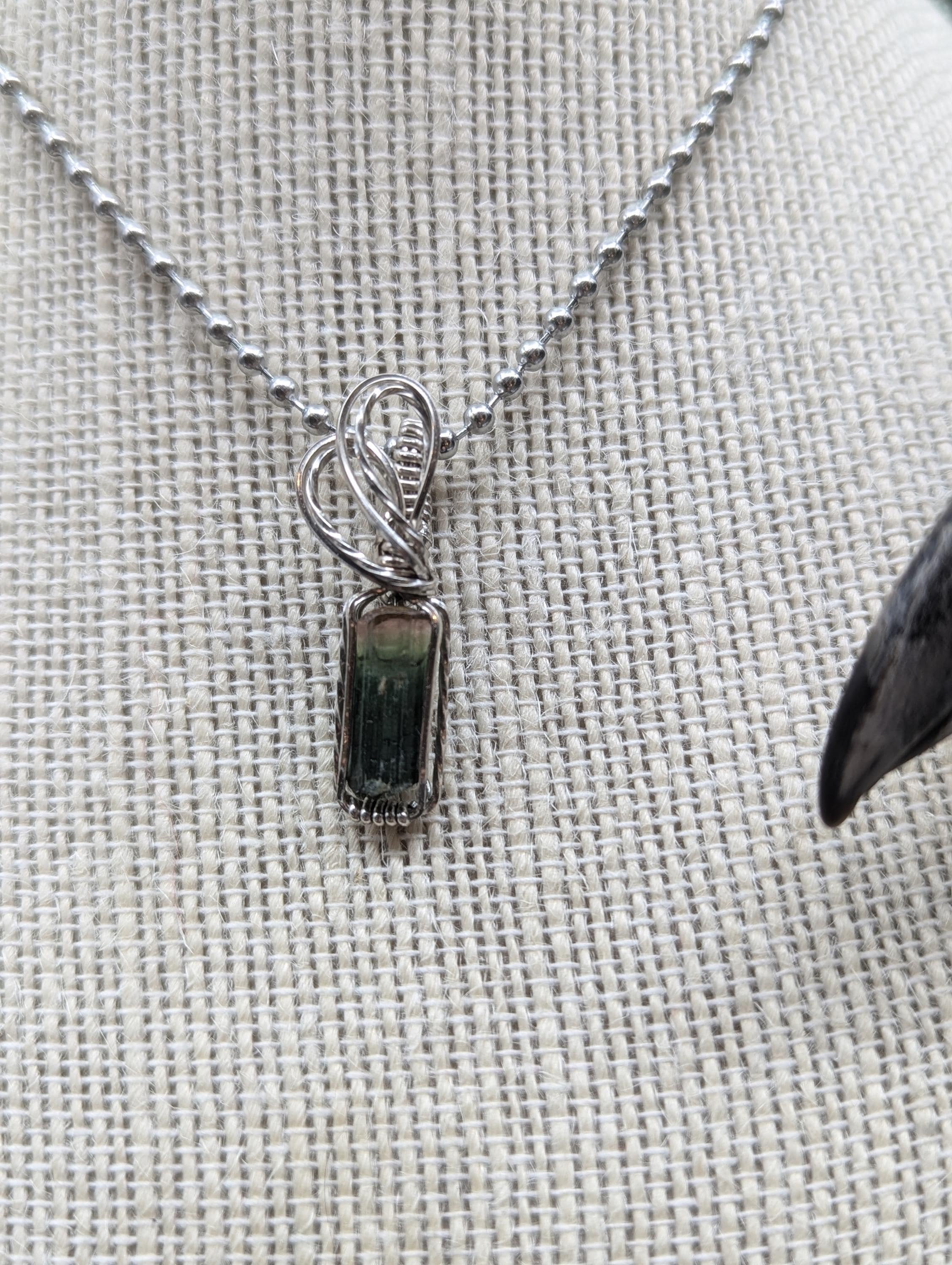 Stunning watermelon tourmaline transitions from pink to deep green, elegantly wire-wrapped in sterling silver with a graceful double swirl bail, showcasing the gemstone as the centerpiece.
