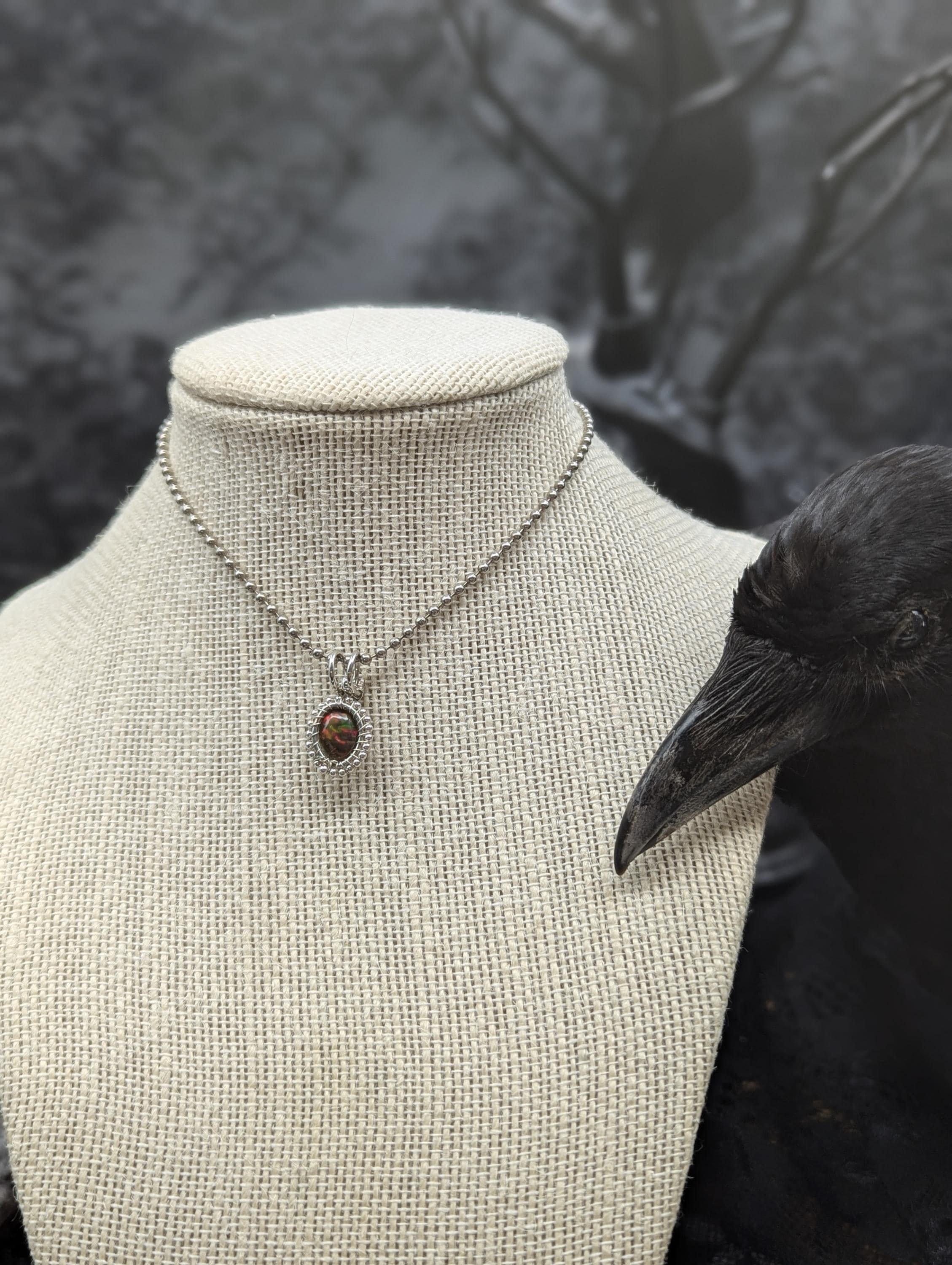 Discover this exquisite Ethiopian black opal sterling wire-wrapped pendant, elegantly accented with shimmering silver beads, showcasing a dazzling spectrum of colors.