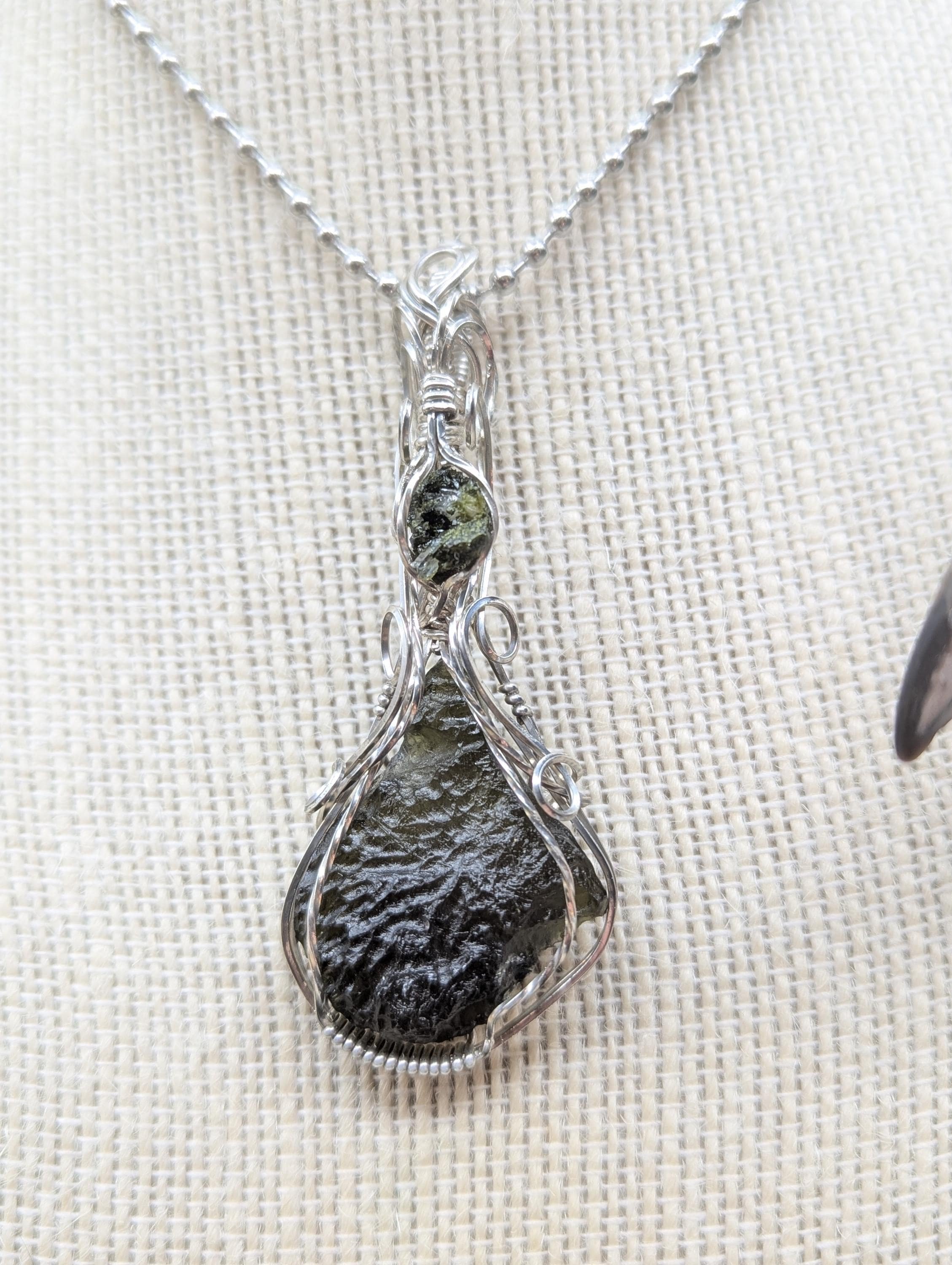 An exquisite 5.4-gram teardrop-shaped green moldavite pendant in sterling silver, elegantly wrapped with a small piece of epidote in quartz above the moldavite.