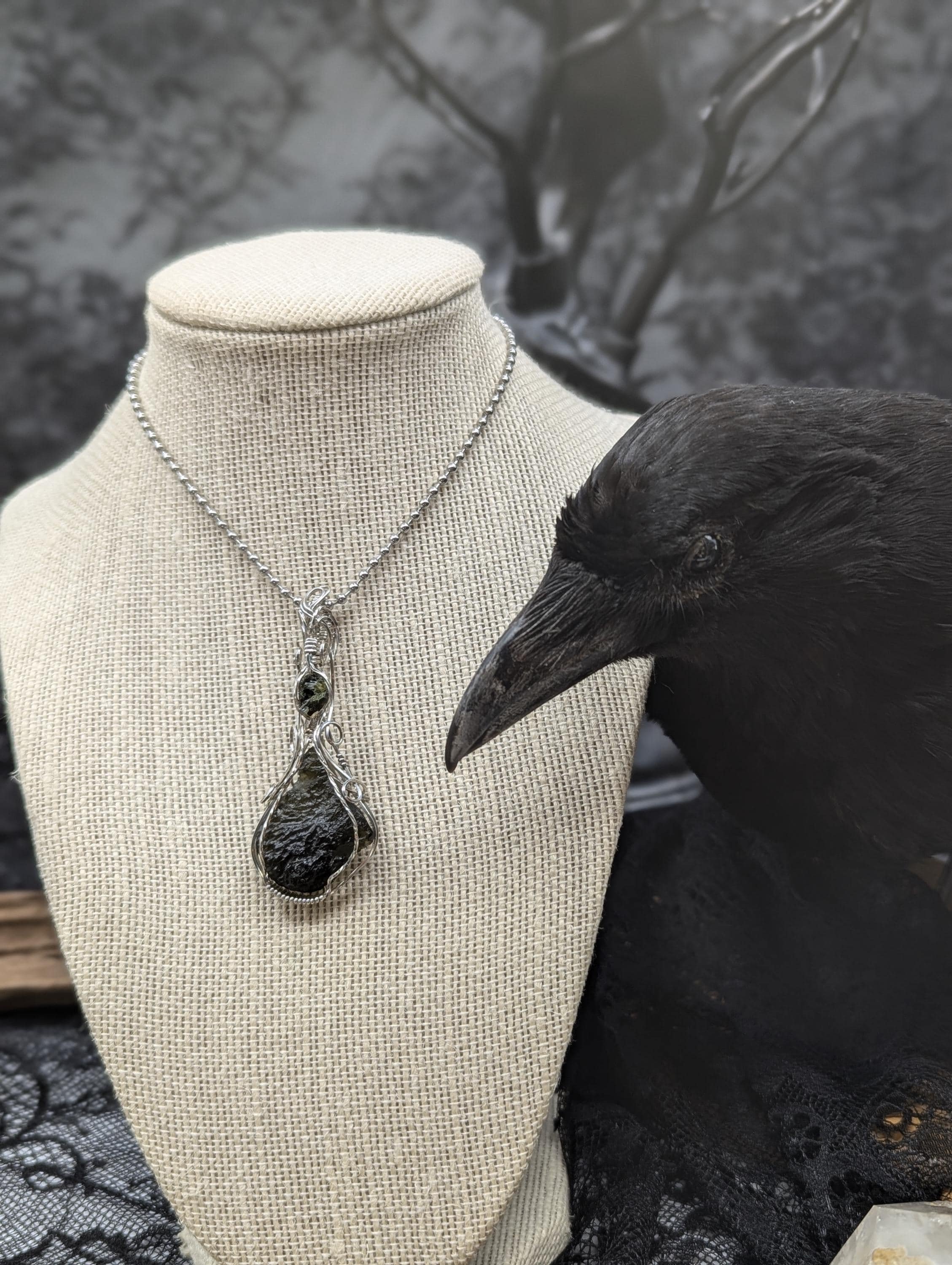 An exquisite 5.4-gram teardrop-shaped green moldavite pendant in sterling silver, elegantly wrapped with a small piece of epidote in quartz above the moldavite.