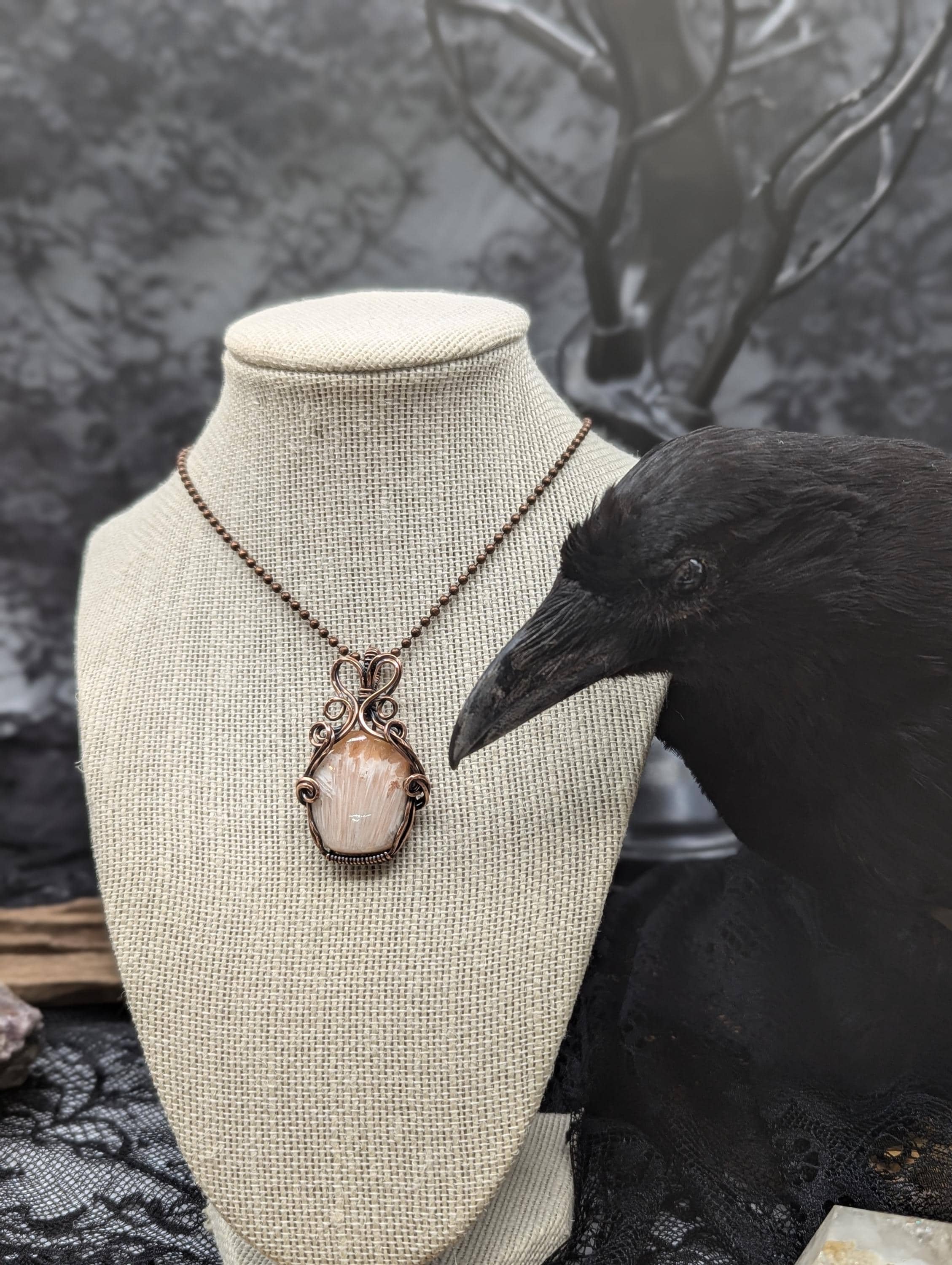Peach Scolecite polished pendant wrapped in antiqued copper wire features an elegant wavy wire bail, with wire twisting and cascading down both sides of the scolecite.