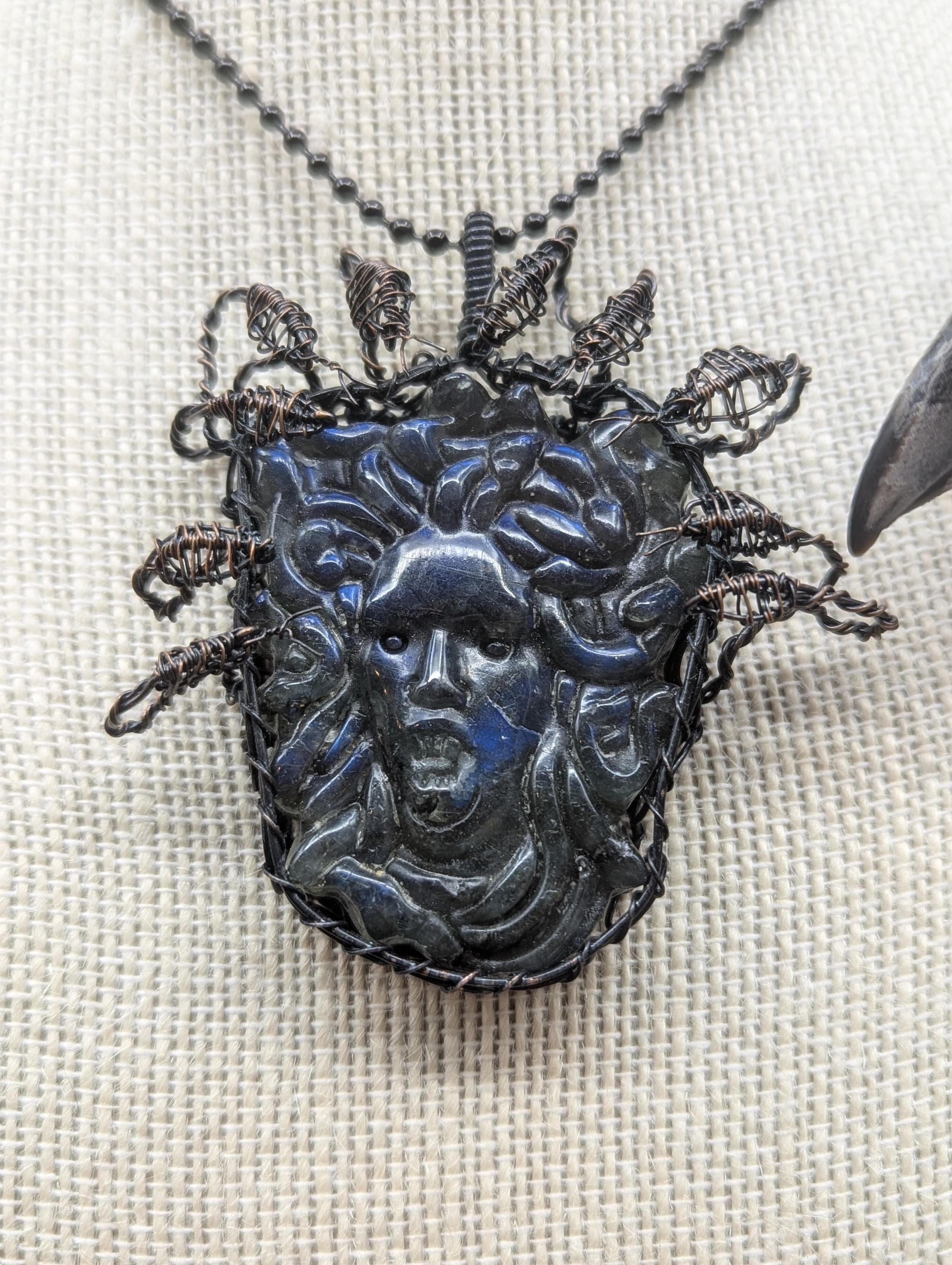 A beautifully carved blue medusa head pendant, wire-wrapped in copper, features 10 intricate 3D snake heads elegantly positioned around and above it.
