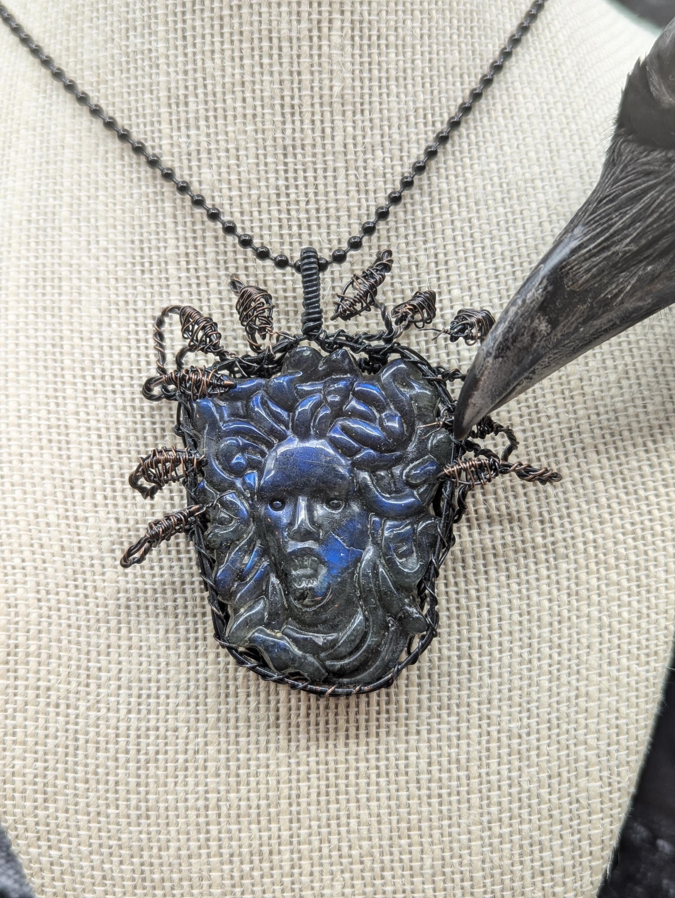 A beautifully carved blue medusa head pendant, wire-wrapped in copper, features 10 intricate 3D snake heads elegantly positioned around and above it.