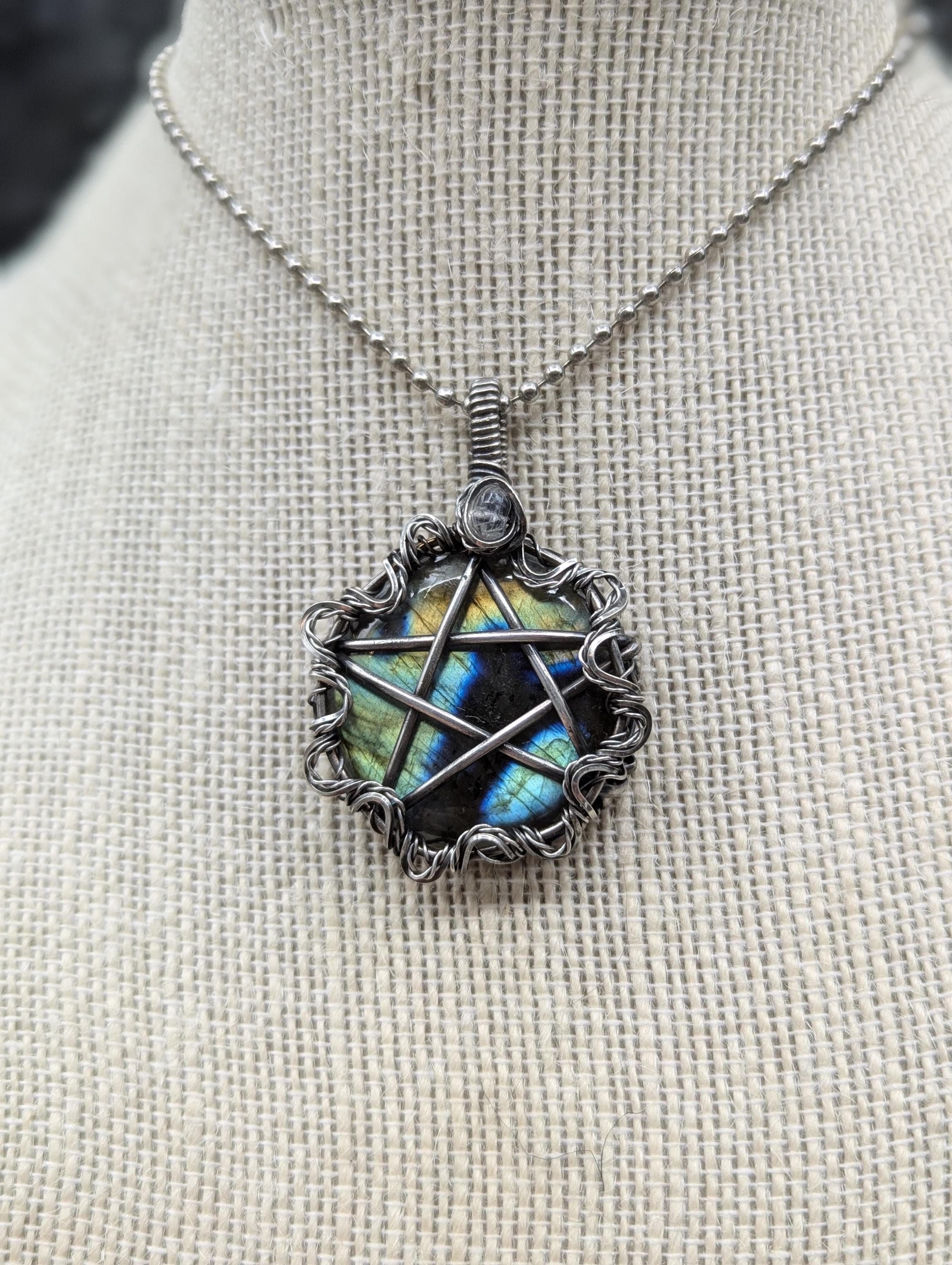 Stunning round labradorite pendant, elegantly wire-wrapped with a striking pentagram design. Enhanced by a wavy twisted wire border and a labradorite bead on the bail.