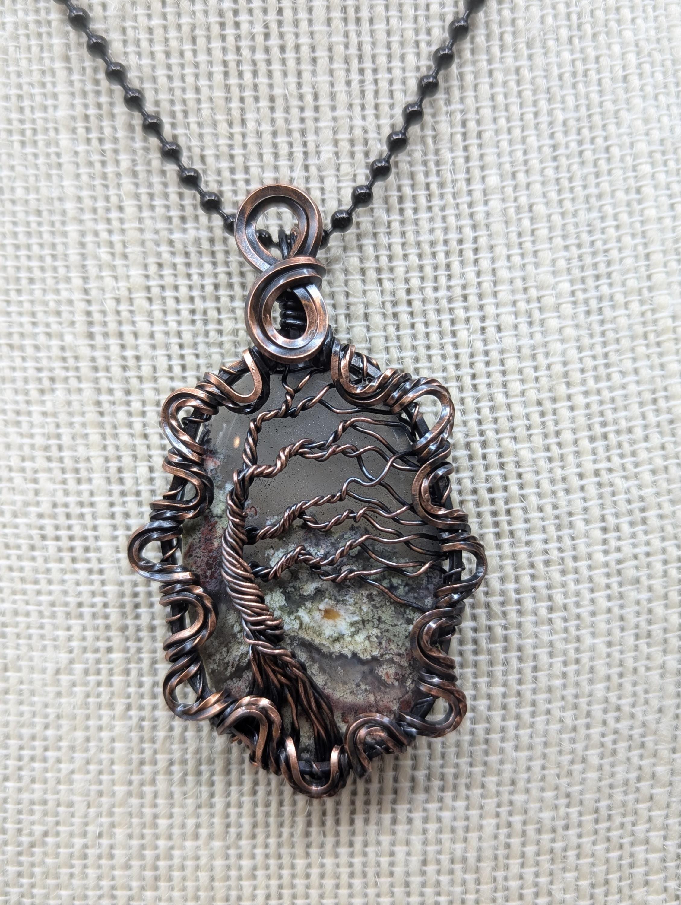 A stunning teardrop garden quartz pendant, elegantly wire-wrapped with a tree of life design that gives a 3D leaf effect, complete with a twisted border and infinity bail.