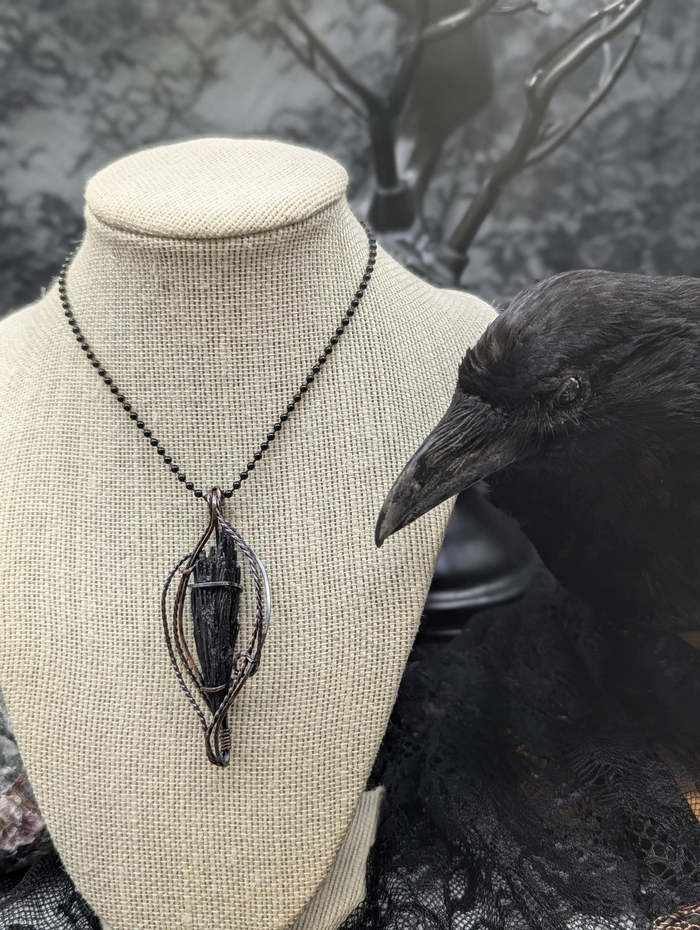 Explore this exquisite Black Kyanite pendant, artfully wrapped in copper wire. Its stunning feathered design and twisted accents elegantly showcase the kyanite as the centerpiece.
